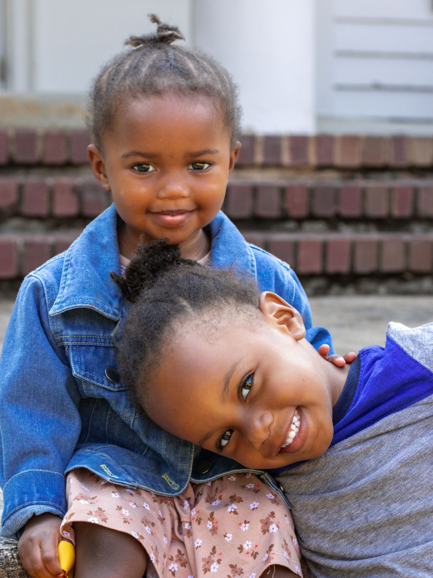Two children in denim and blue outfits smile brightly at the camera.