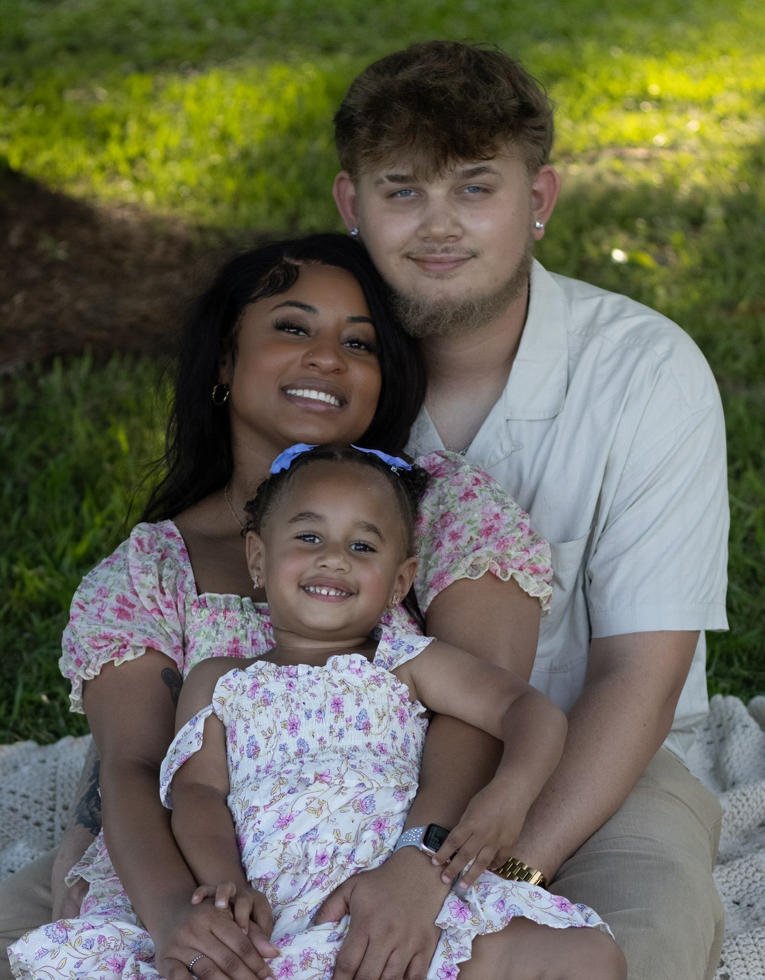 Happy family in matching floral outfits pose together on grass during an outdoor spring photoshoot Ridgeway SC captured by Raley and Roots.