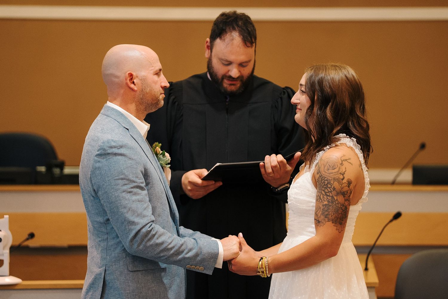 A couple shares an emotional embrace with an officiant during what appears to be a wedding ceremony.