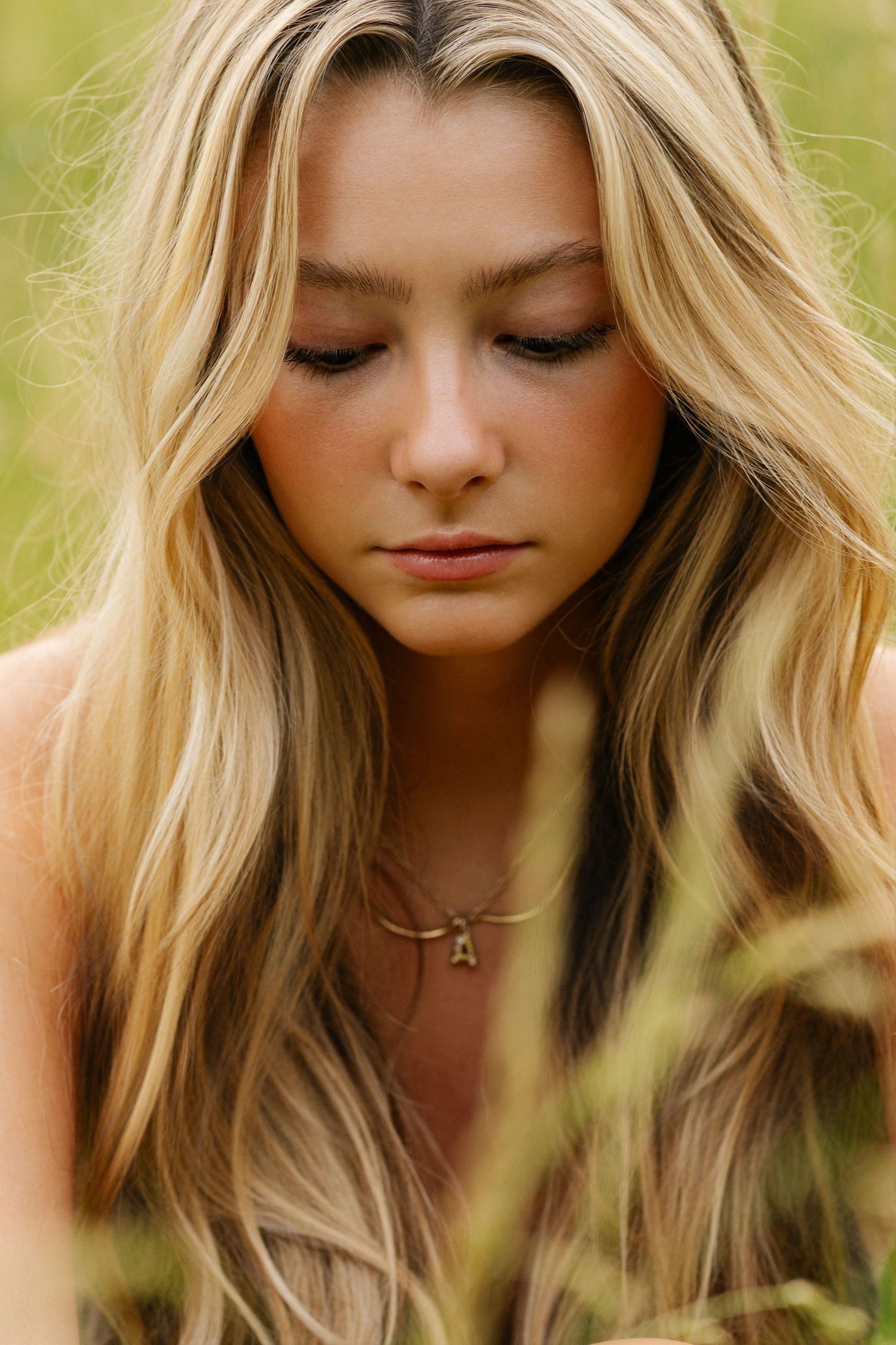 Artistic portrait photography showing wavy blonde hair against soft natural lighting in an outdoor setting.