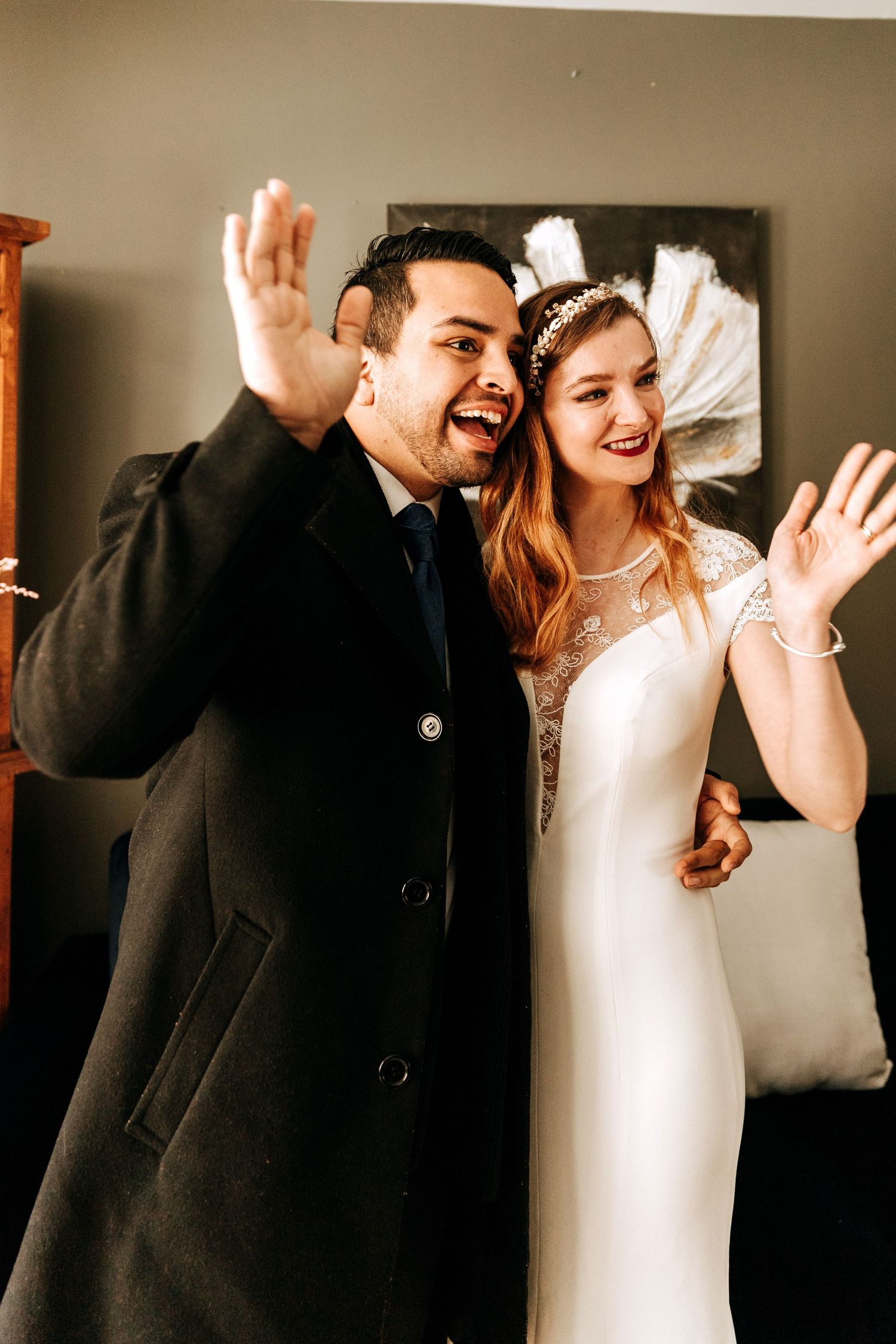 Joyful couple celebrating their wedding day, expressing excitement with raised hands and big smiles.