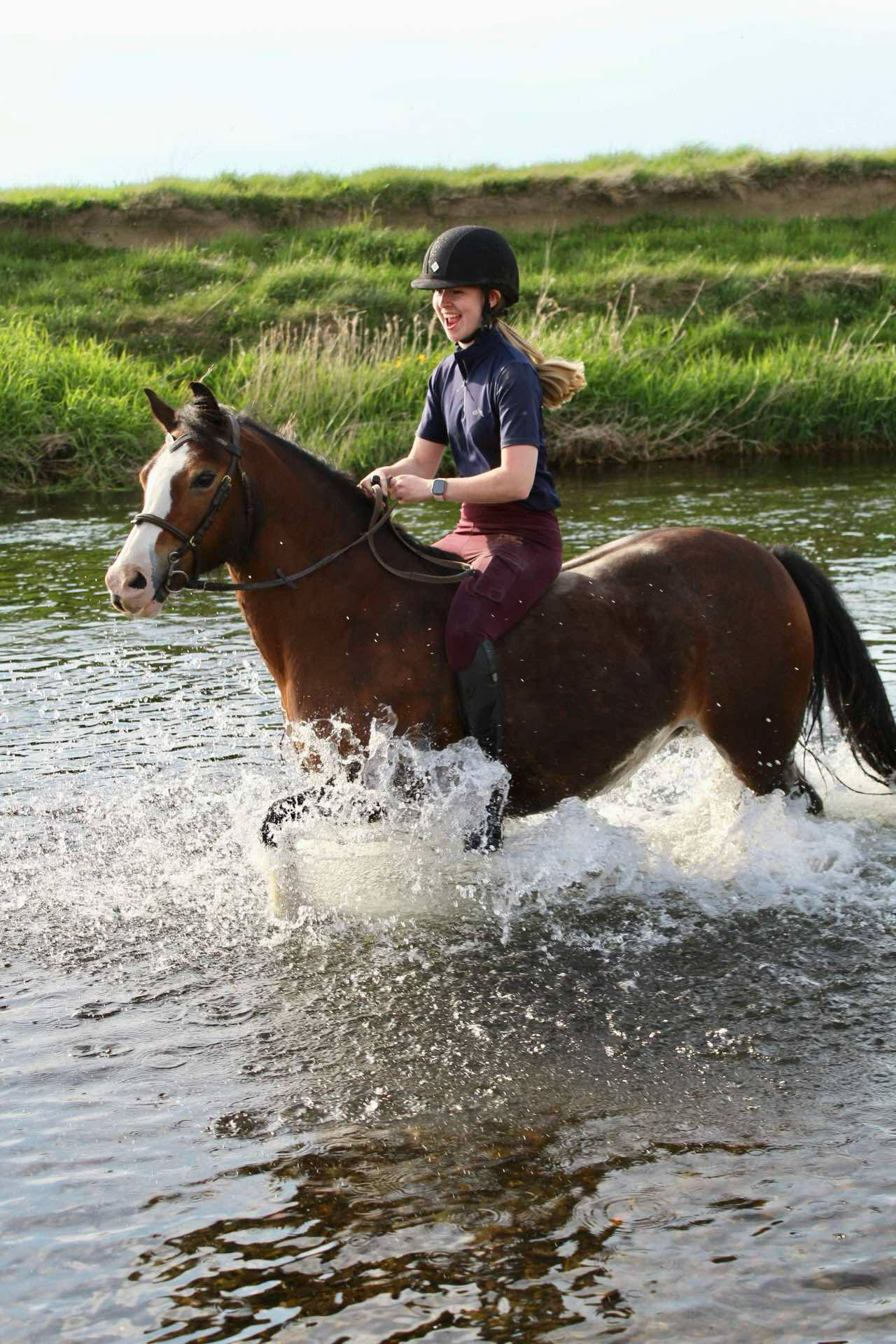 human on horse riding through river