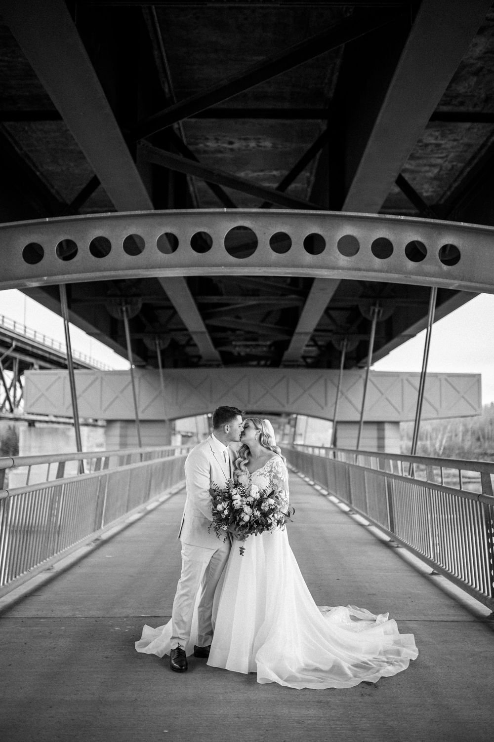 Black and white composition of a wedding couple in an architectural passageway with industrial design elements.