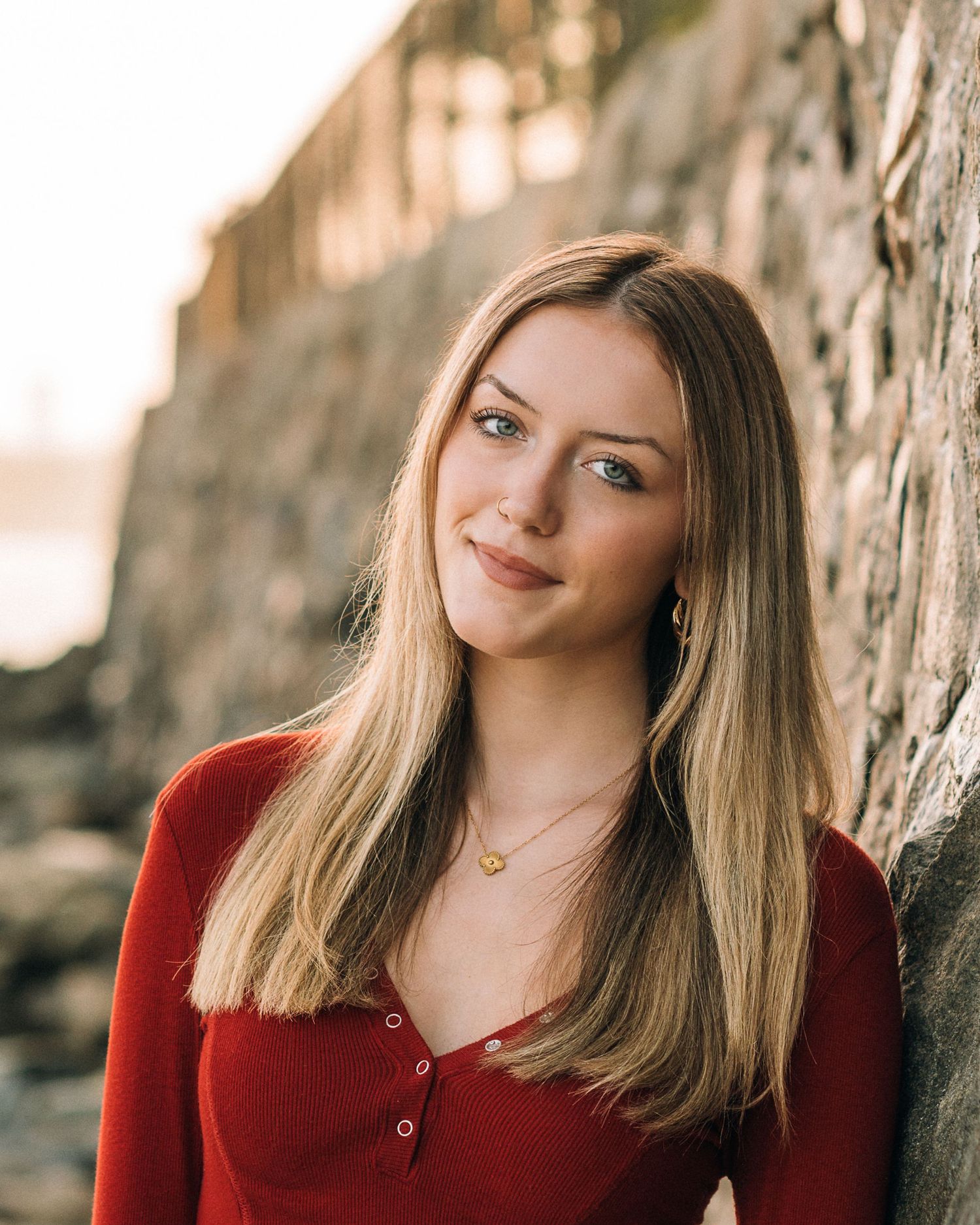 Close up portrait against stone wall with warm sunset lighting.