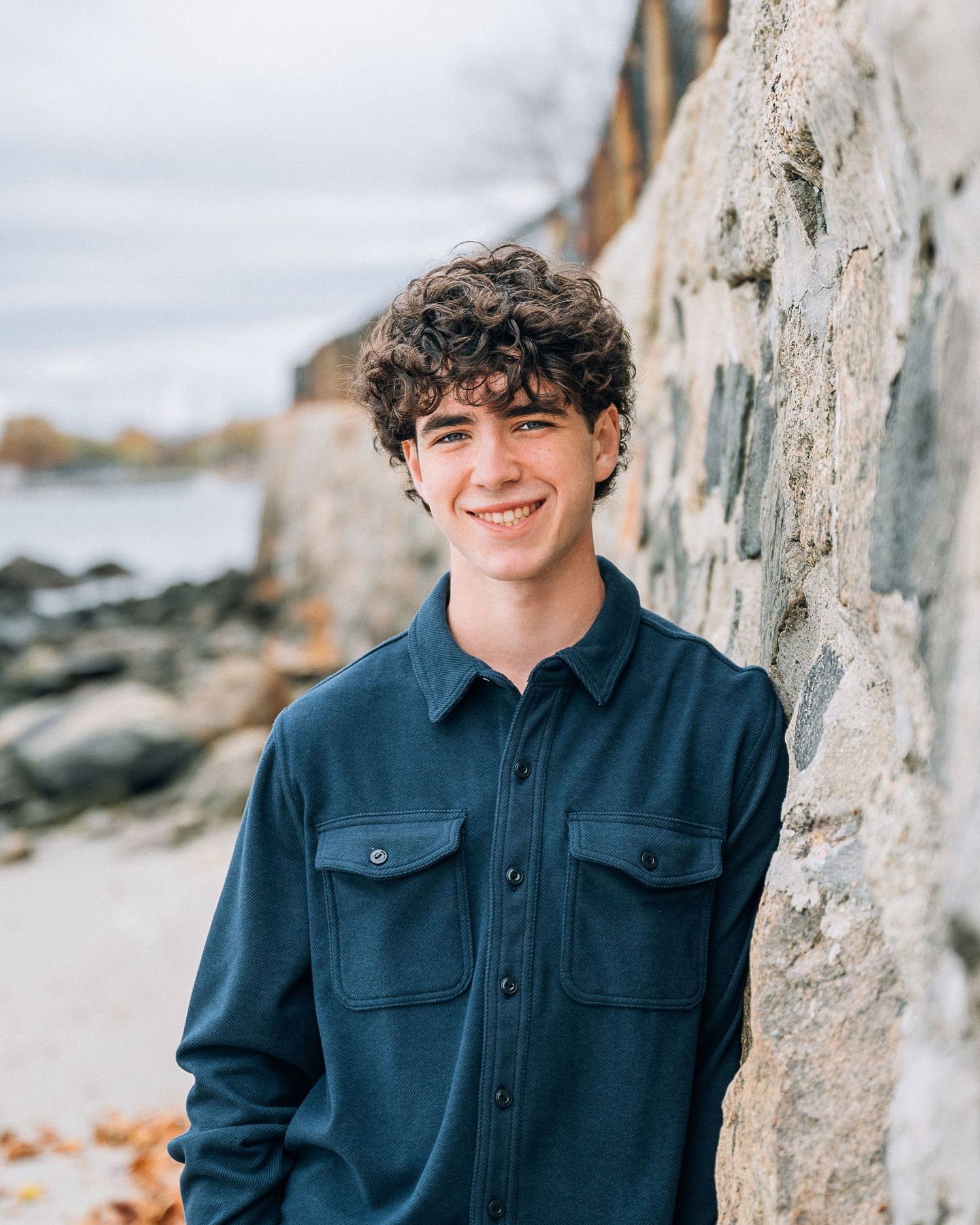 Outdoor professional photo near a rocky coastline featuring dark blue button-up shirt.