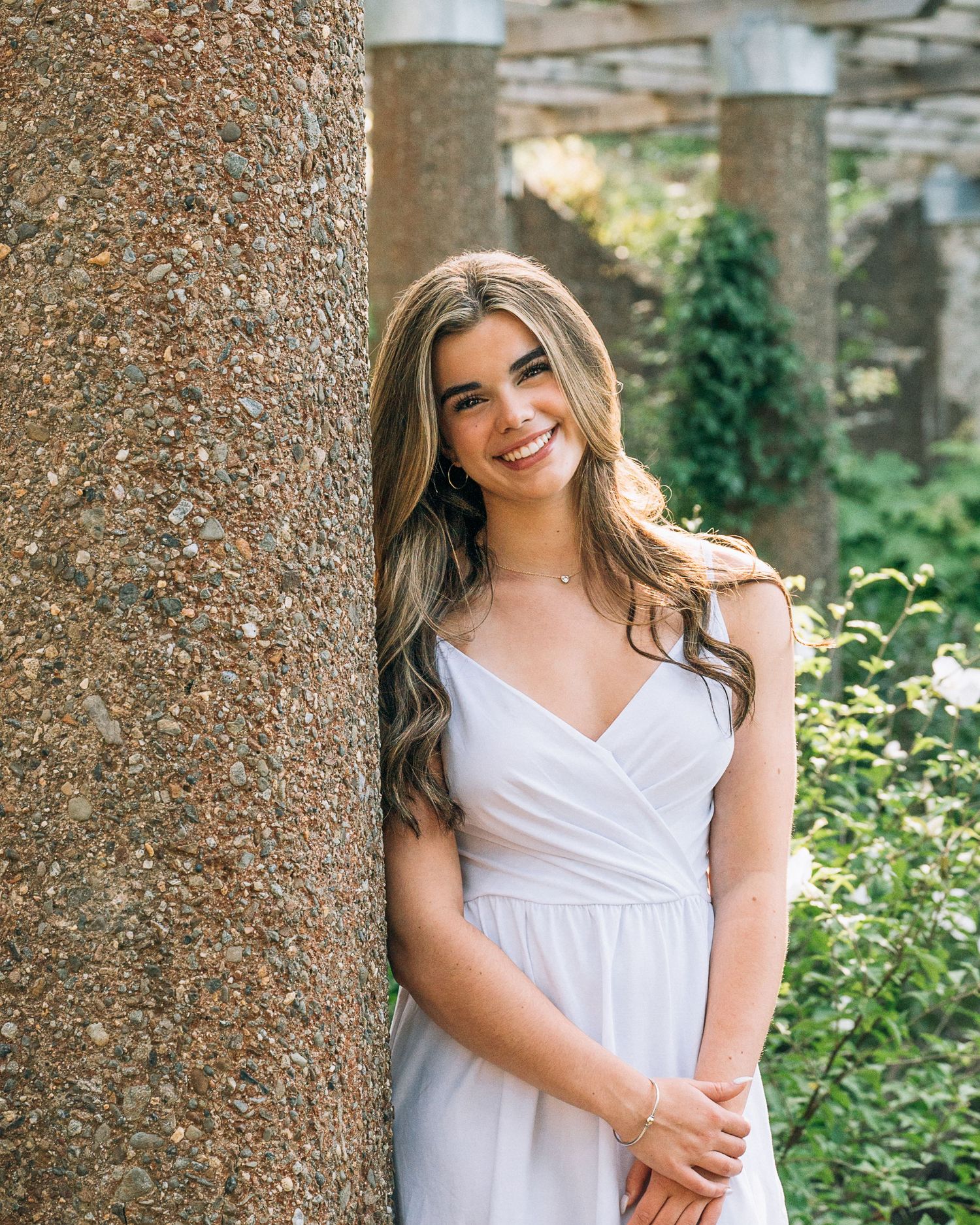 Portrait against textured stone pillar in garden setting.
