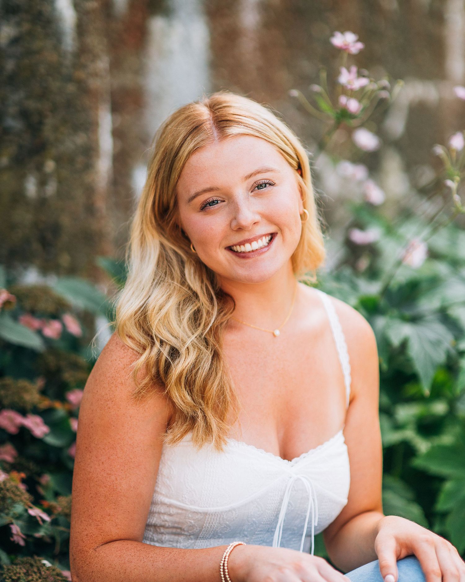 Casual summer portrait with bright smile against garden background.
