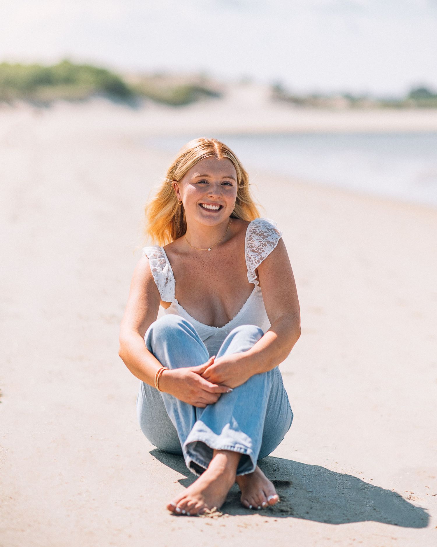 Relaxed beach portrait in casual attire sitting on sand.