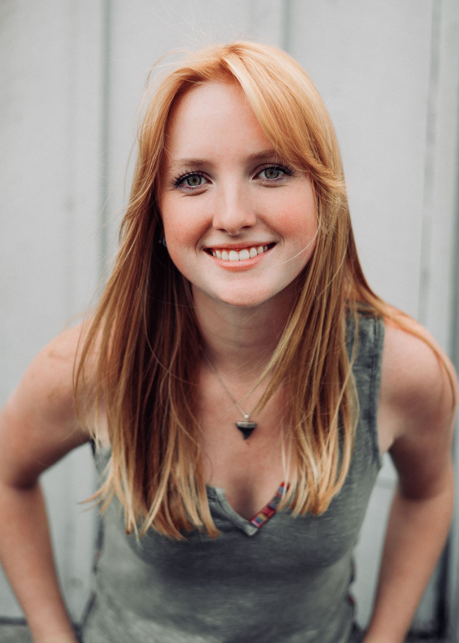 Portrait showing someone in casual attire smiling against a light background.