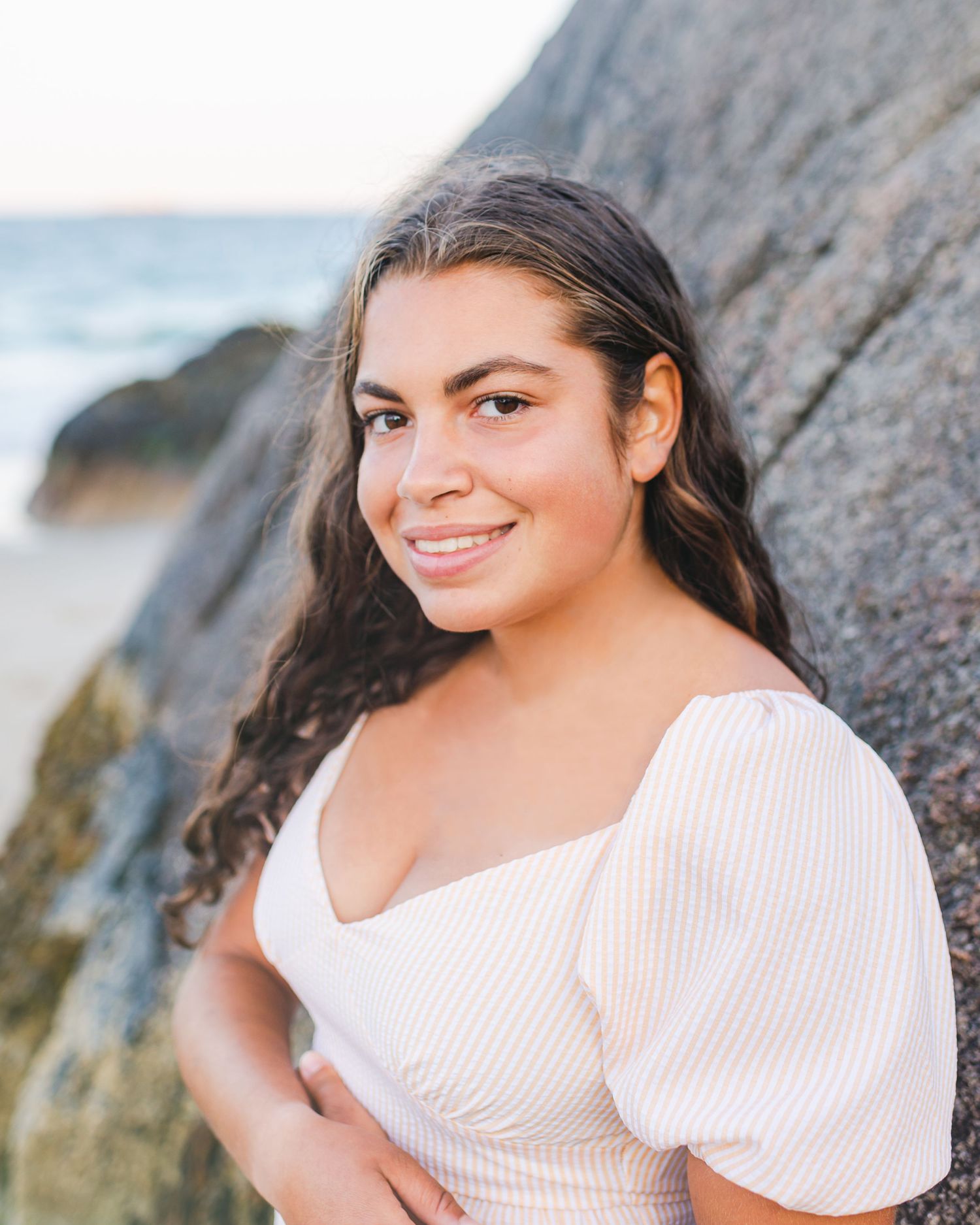 Close-up seaside portraits with rocky coastal backdrop at golden hour.