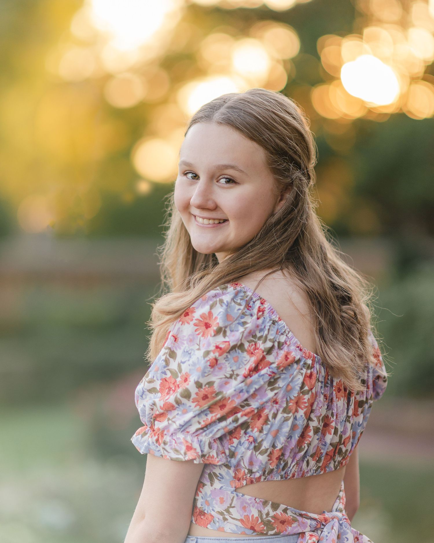 Person wearing floral print dress poses in golden sunset light.
