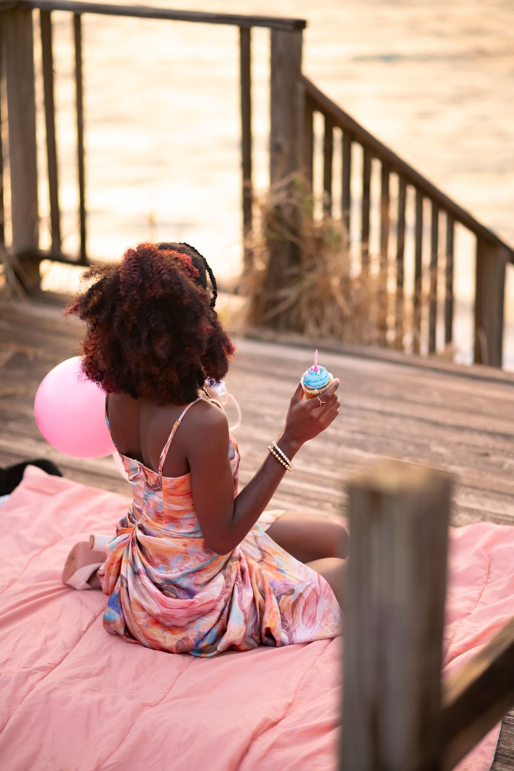 Casual beach portrait on pink blanket with summer dress at sunset.