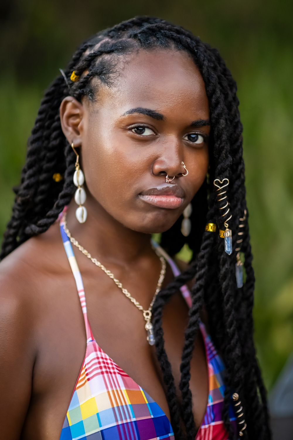 Portrait of a person wearing colorful jewelry and braided hairstyle with ornate decorations.