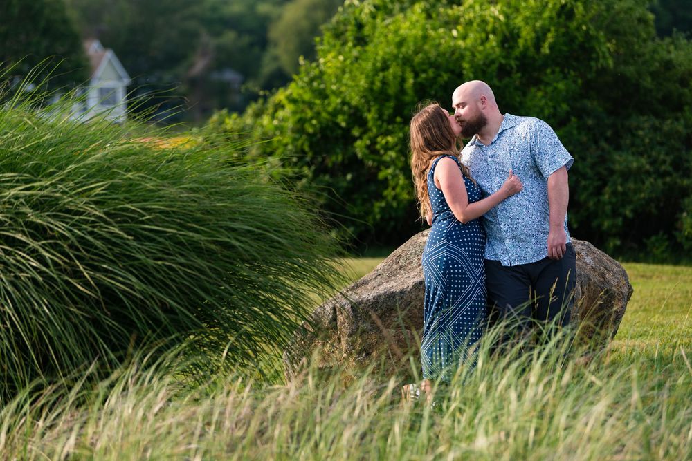 A loving couple shares romantic moments in a golden field at sunset during their outdoor engagement photo session.
