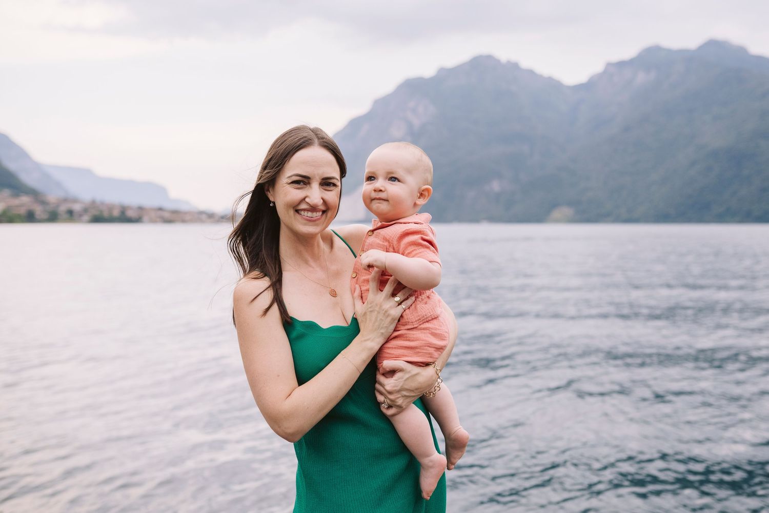 Mamma tiene in braccio il suo bimbo lattante sullo sfondo dei paesi del Lago di Como