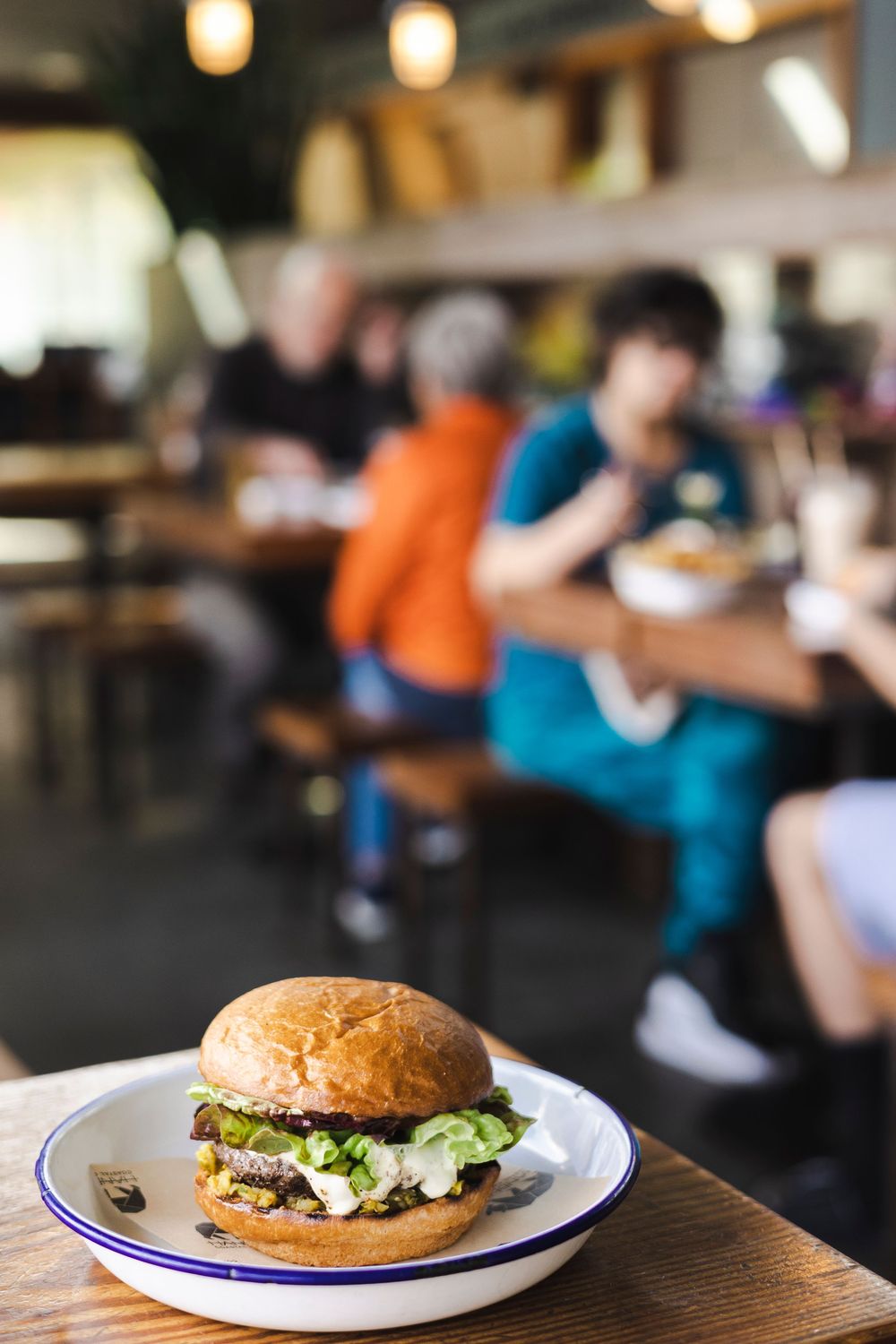 Gourmet burgers with fresh toppings served on white plates in a casual restaurant setting.