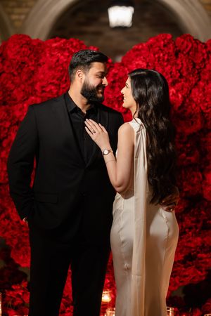 A romantic couple shares intimate moments in front of a stunning backdrop of vibrant red roses during their wedding celebration.