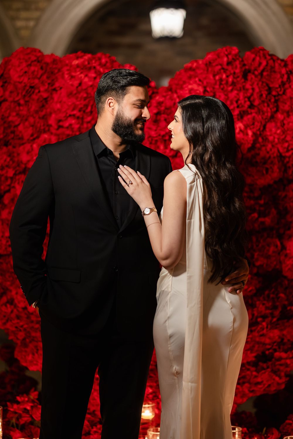 A romantic couple shares intimate moments in front of a stunning backdrop of vibrant red roses during their wedding celebration.