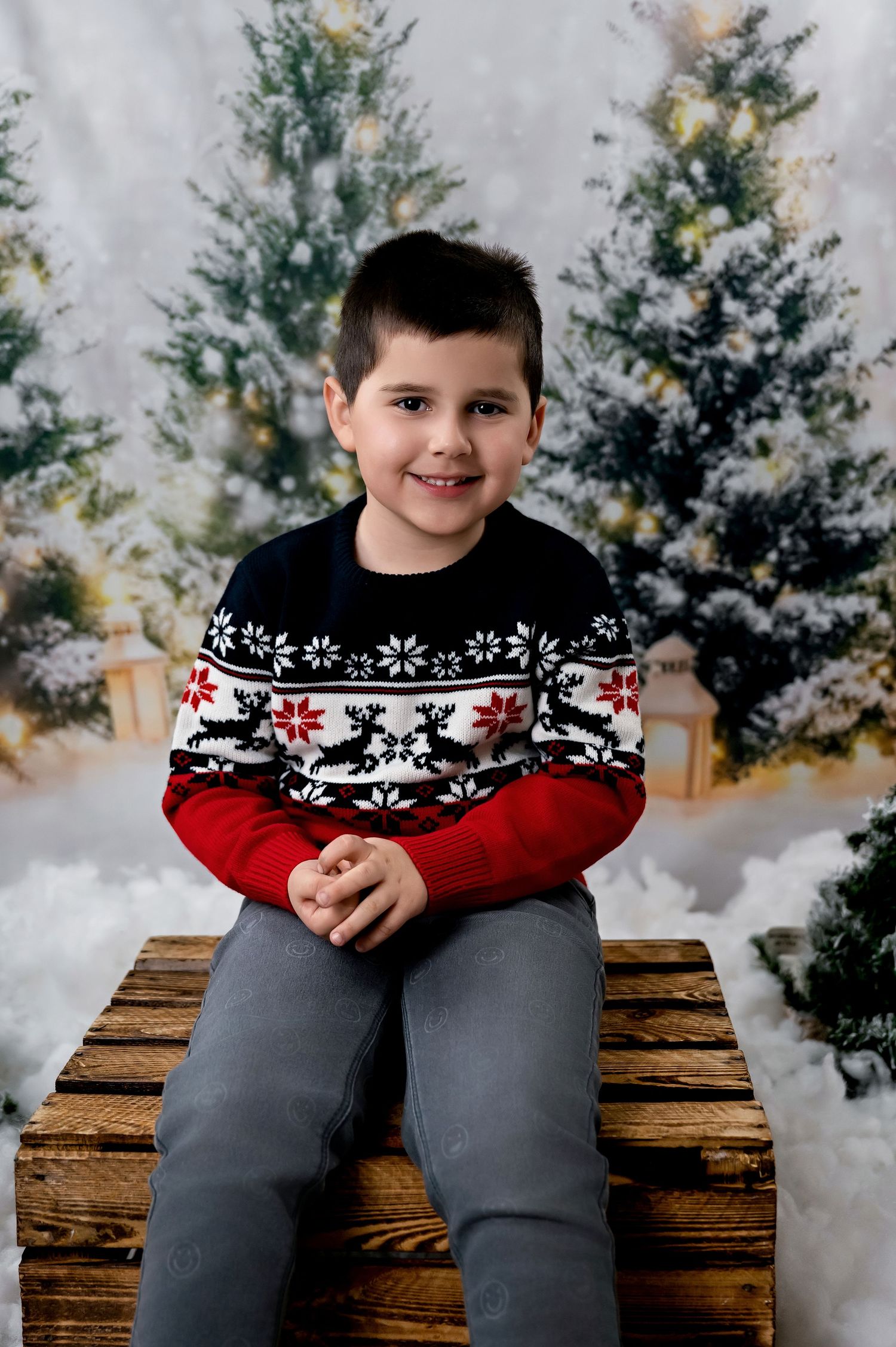 A festive holiday portrait in front of decorated Christmas trees with someone wearing a patterned winter sweater.