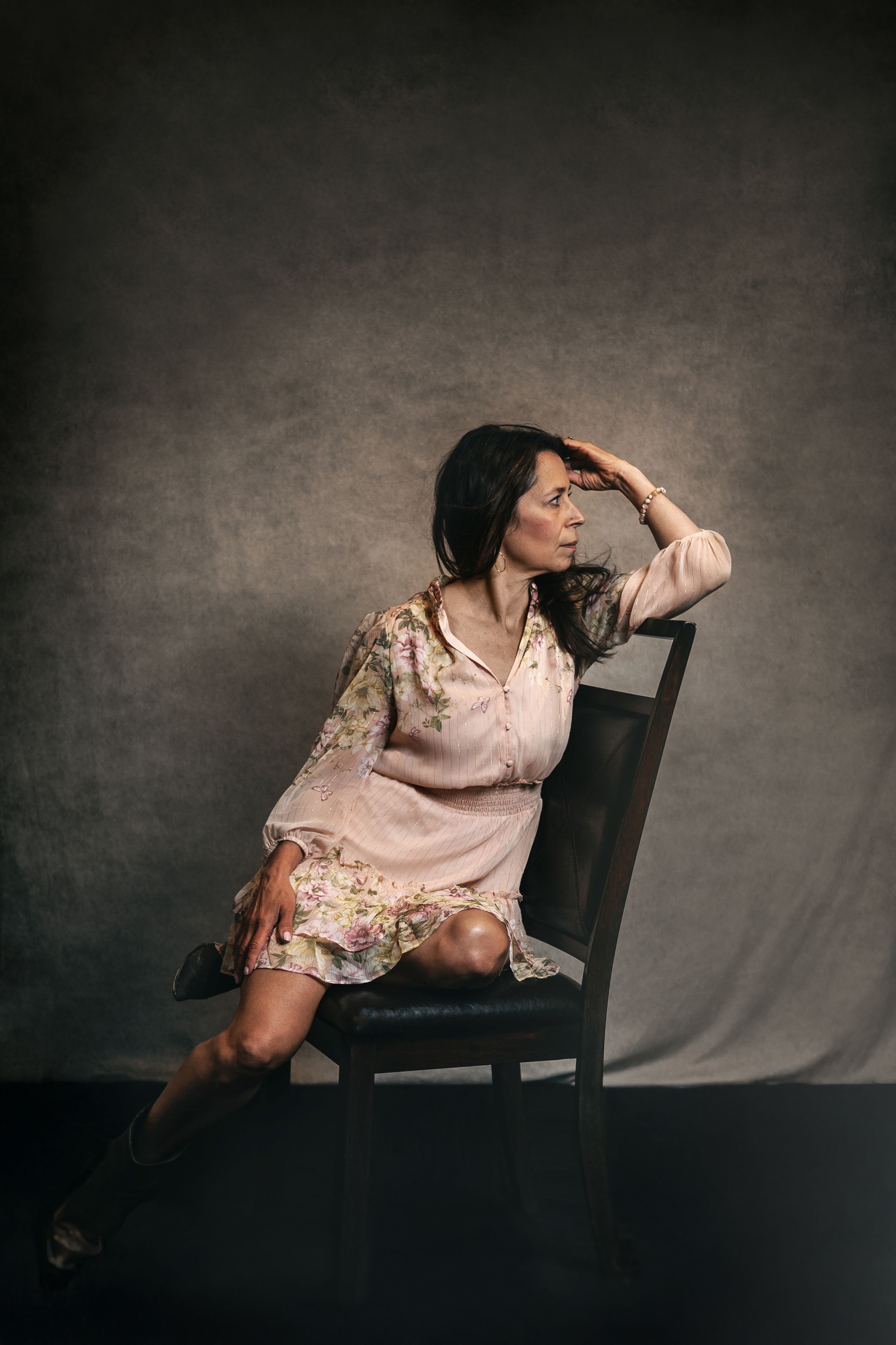 A series of moody artistic portraits featuring someone in a floral dress posing on a wooden chair against a dark backdrop.