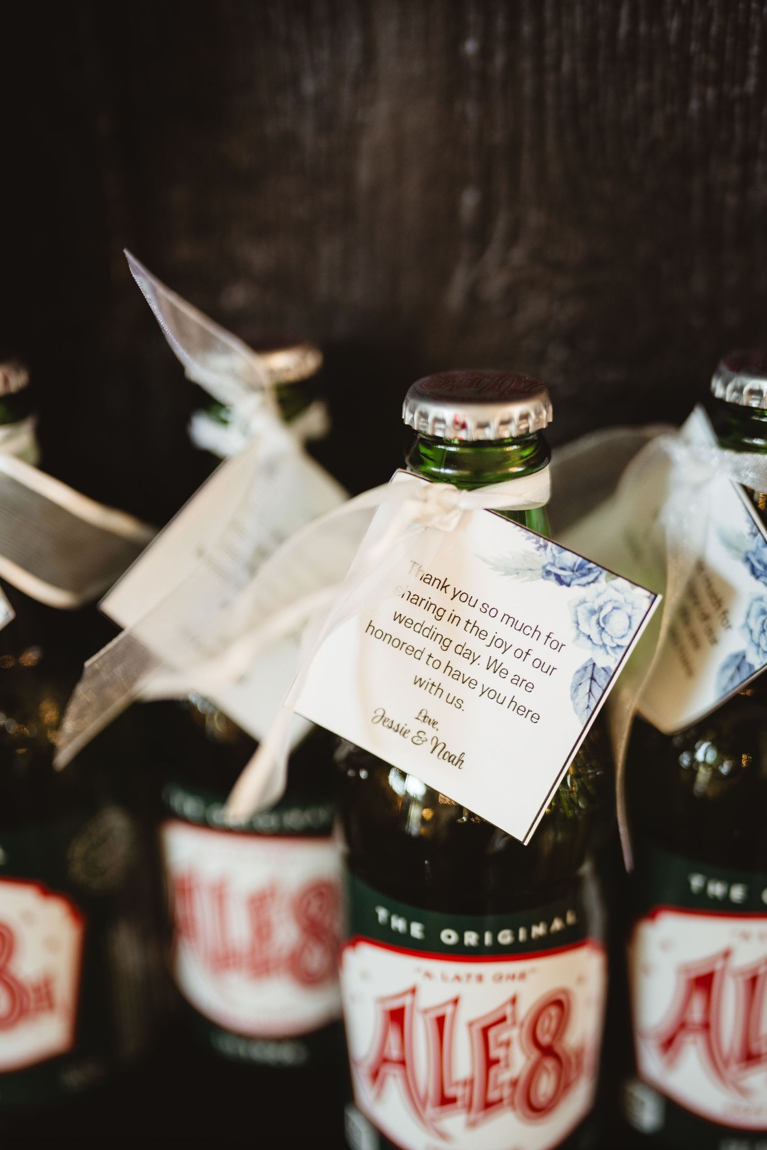 Glass bottles of Ale-8-One soft drink with white paper notes attached to the necks displayed in a dark setting.