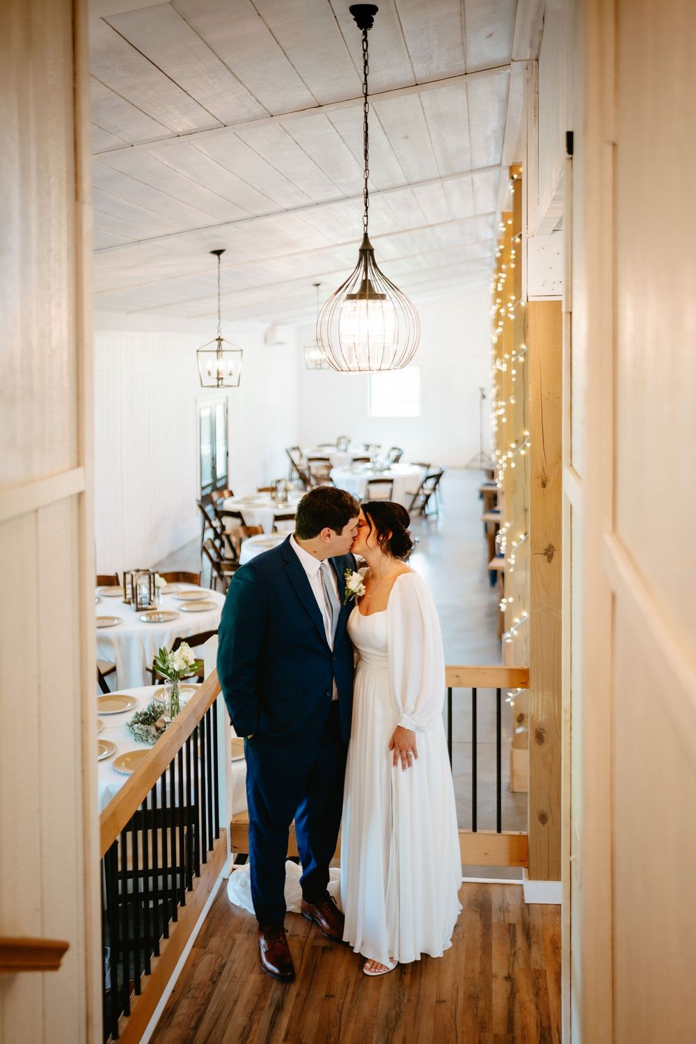 Romantic wedding couple sharing intimate moments in a minimalist venue with hardwood floors and white walls.