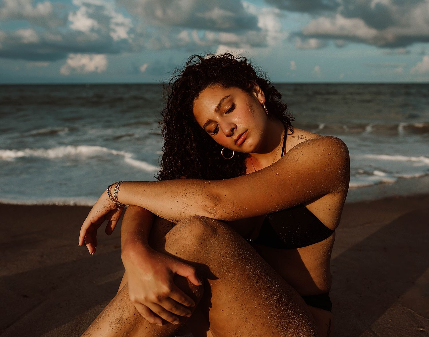 woman sits next to ocean in the sand for Outdoor Beach Shoot