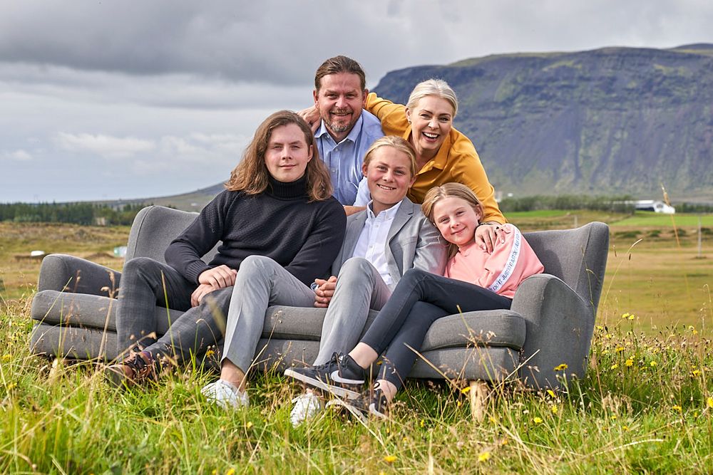 Family group relaxing together on outdoor couch in scenic mountain landscape.