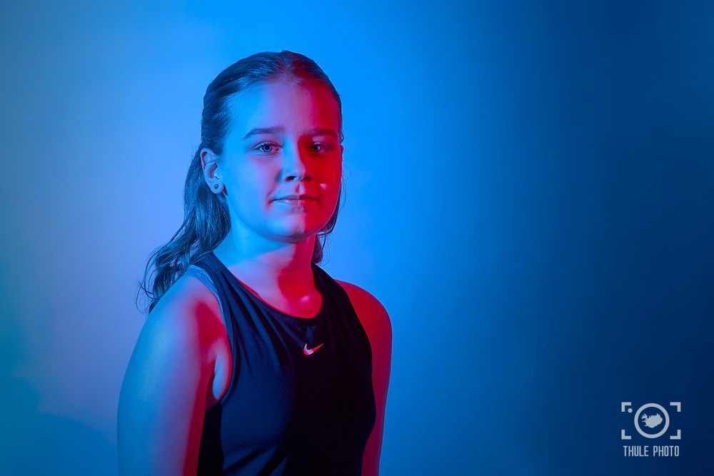 Portrait with dramatic blue and red lighting against dark background.