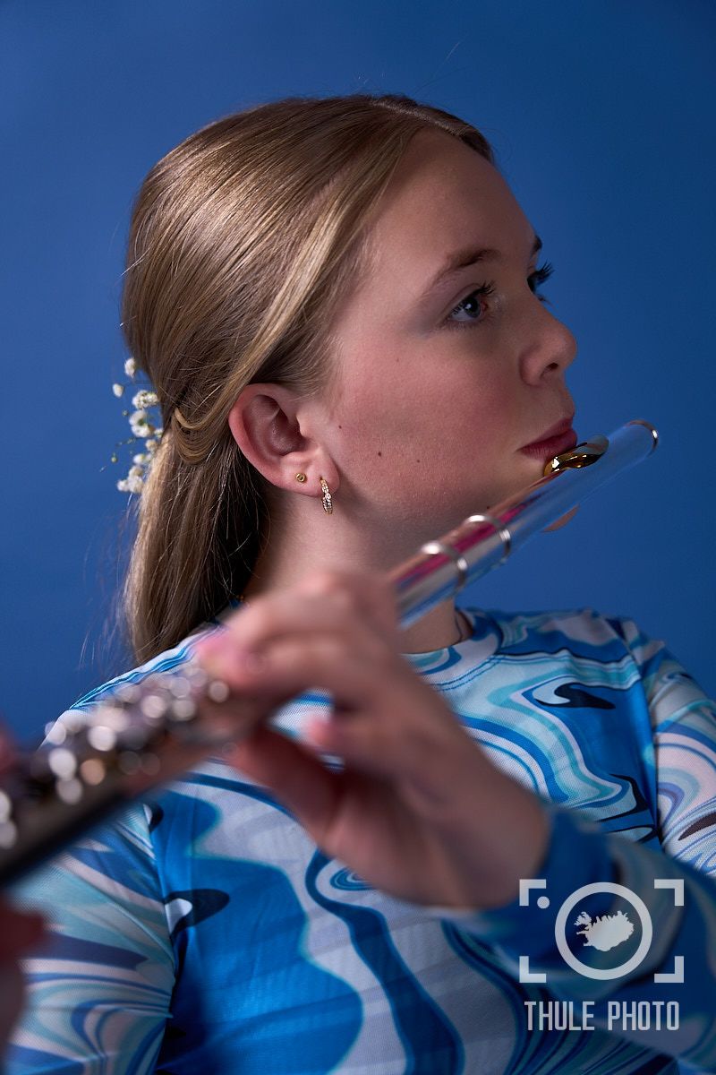 Side profile of flutist performing in blue marbled pattern shirt.