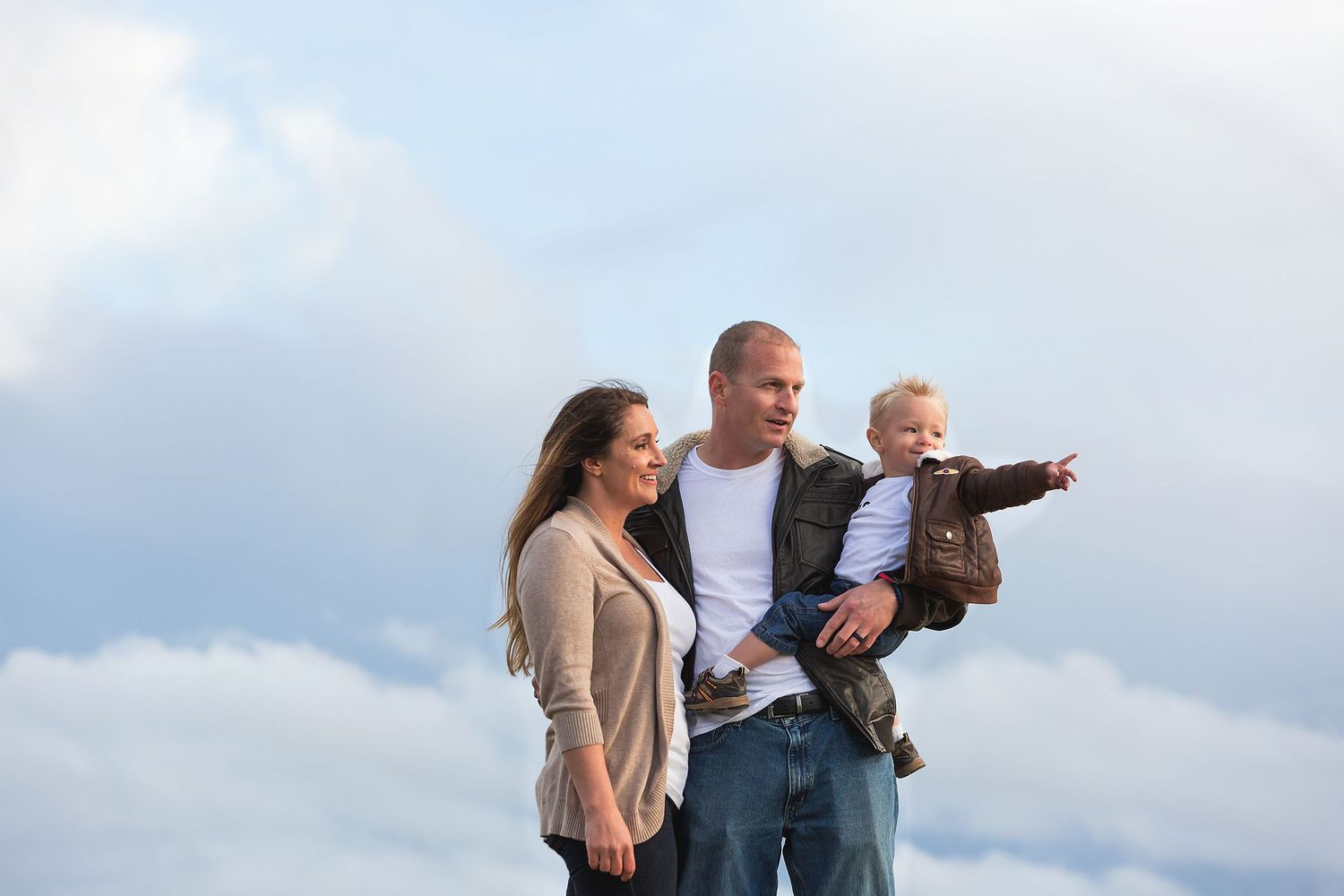 Family pointing and looking into the distance together against cloudy sky.