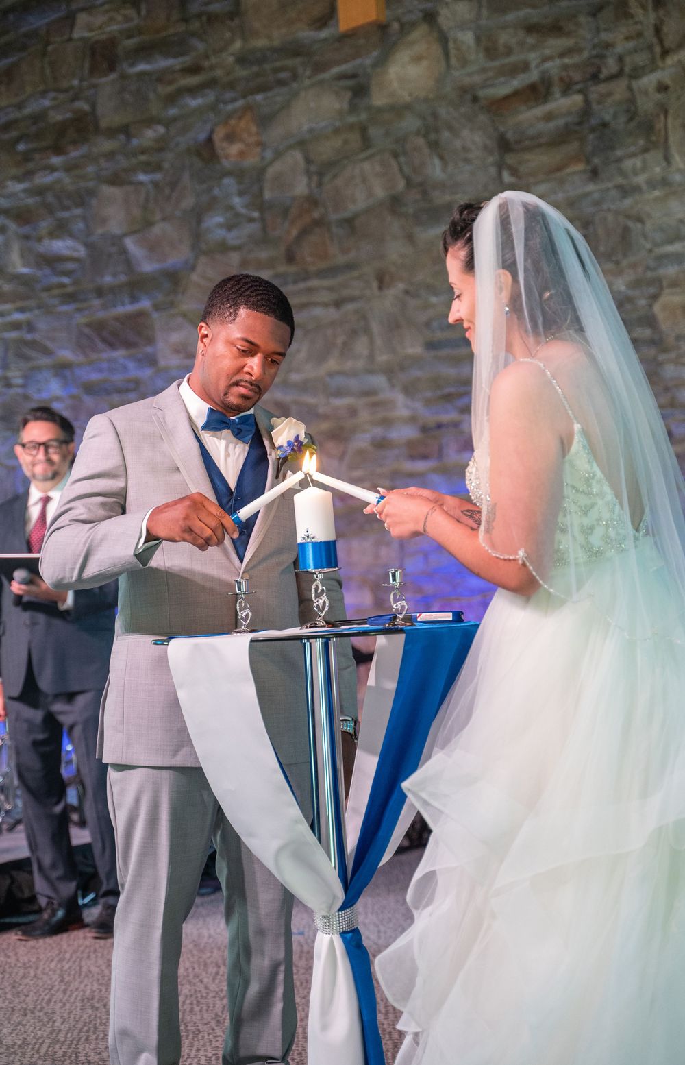 A bride and groom perform a unity ceremony with blue and clear liquids at their wedding celebration.