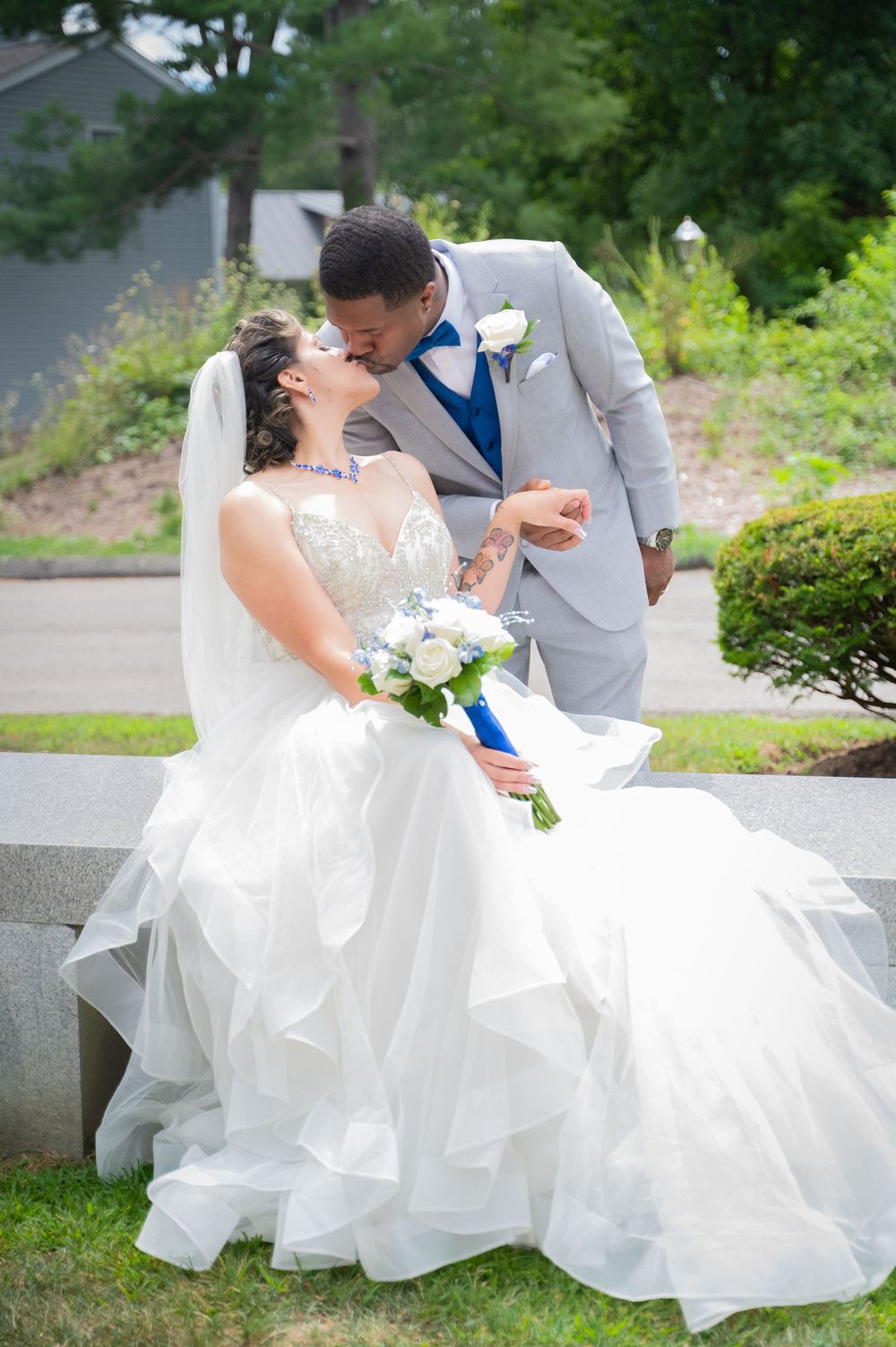 Romantic dip pose in wedding photography showing bride in flowing white dress against green outdoor backdrop.