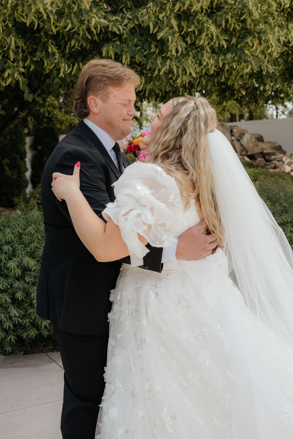 Bride and groom embracing and smiling during emotional outdoor first look moment at wedding venue.