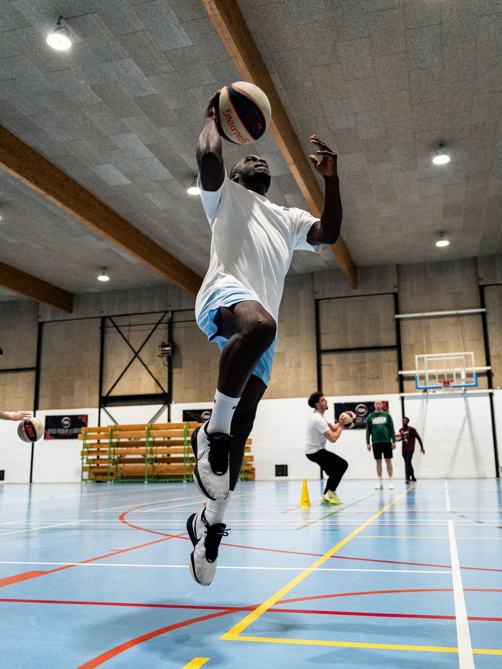Joueur de basket-ball sautant haut pour attraper le ballon pendant un entraînement en salle. Florent Vause