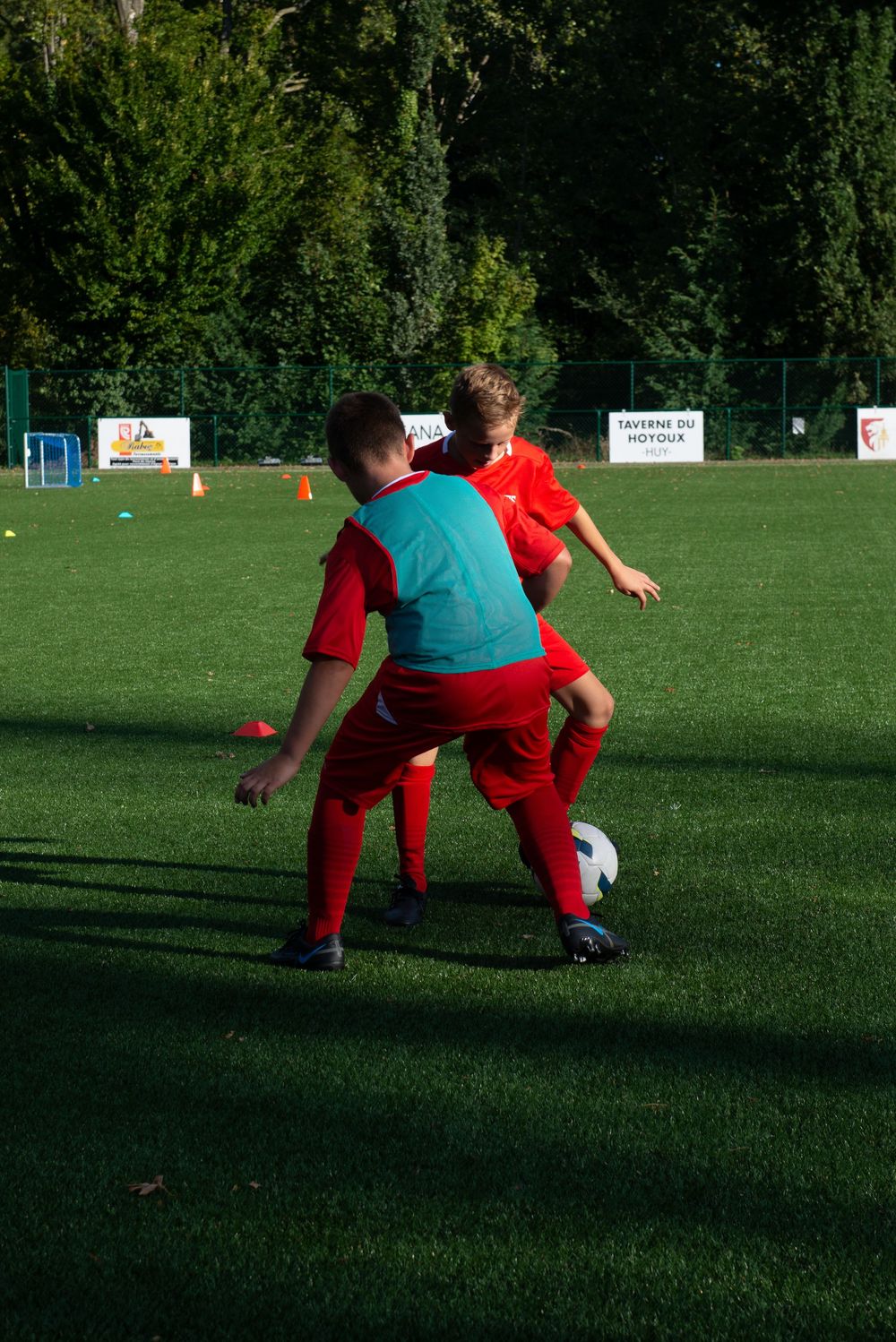 Des joueurs de football en tenue rouge s'entraînent sur un terrain de sport vert. Florent Vause