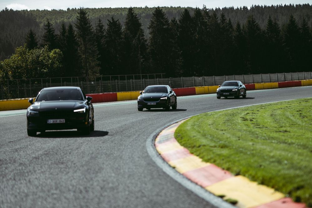 Plusieurs voitures font la course sur un circuit sinueux entouré d'herbe verte et d'arbres. Florent Vause