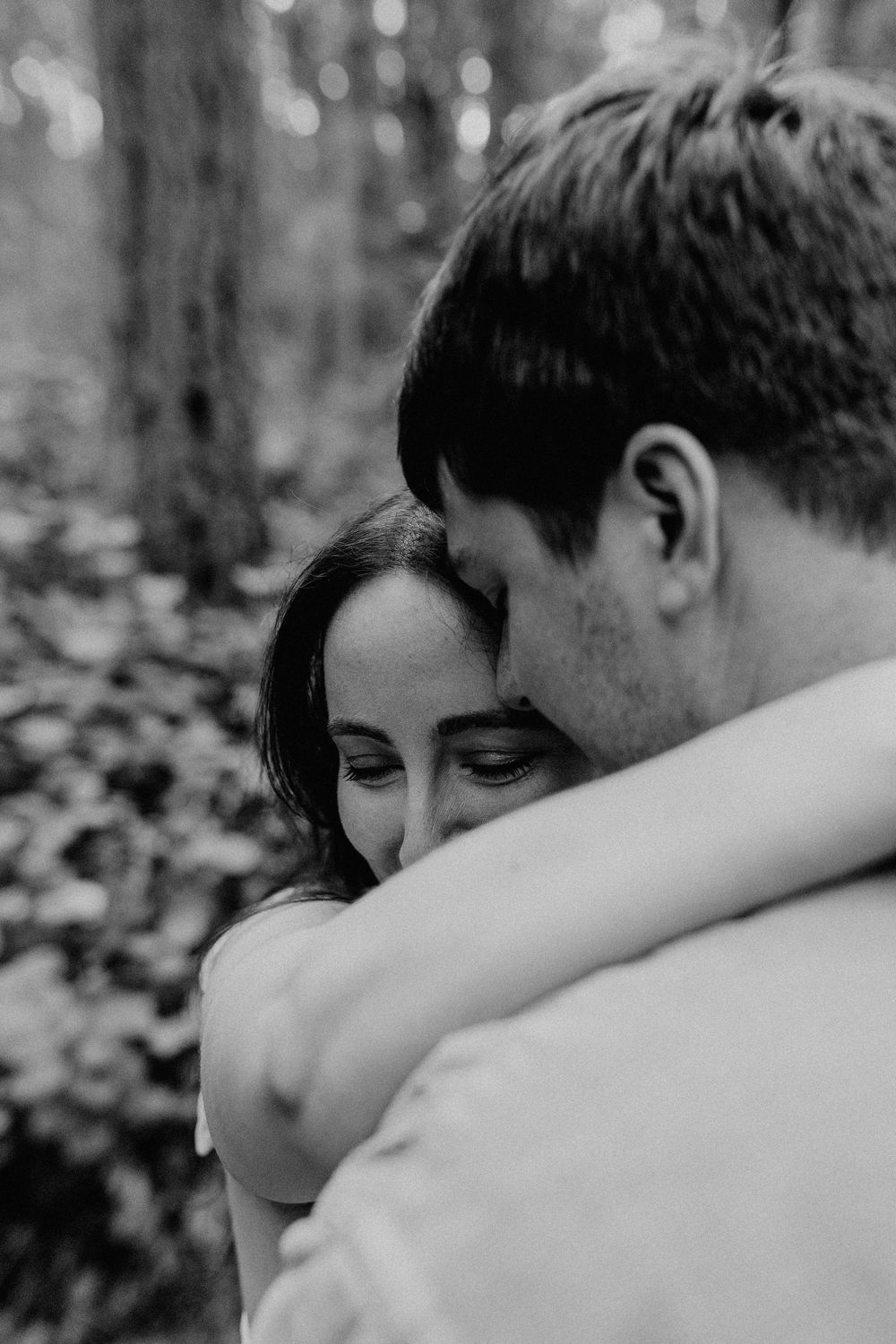 A close-up black and white series of photographs showing an intimate embrace between two people in a wooded setting.