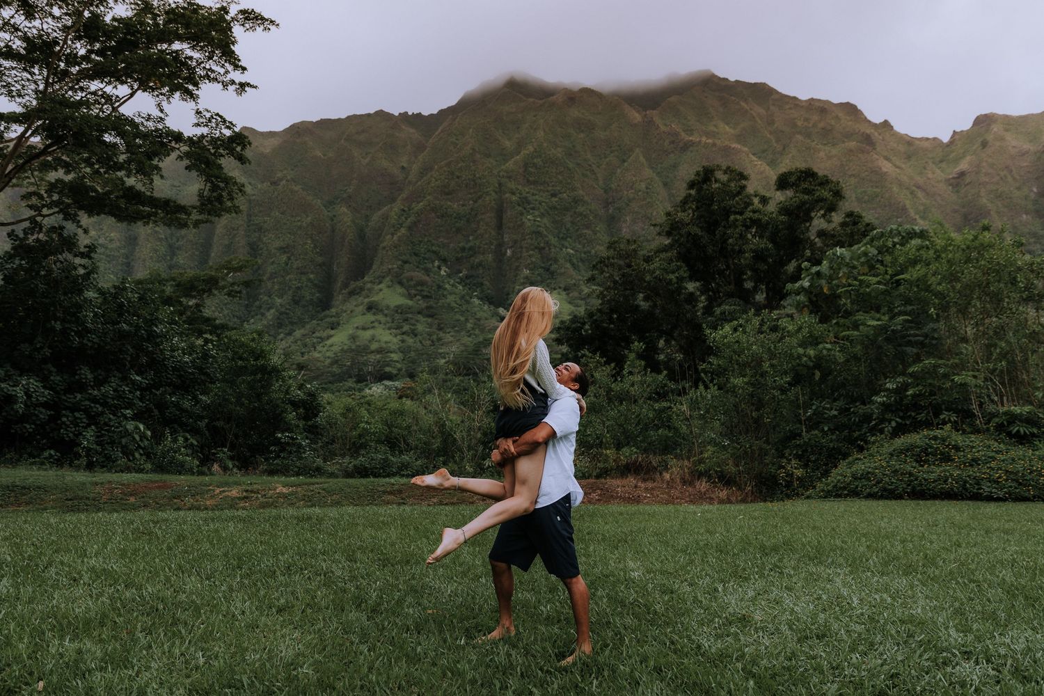 Couple enjoying a romantic moment in front of majestic mountain scenery in Hawaii.
