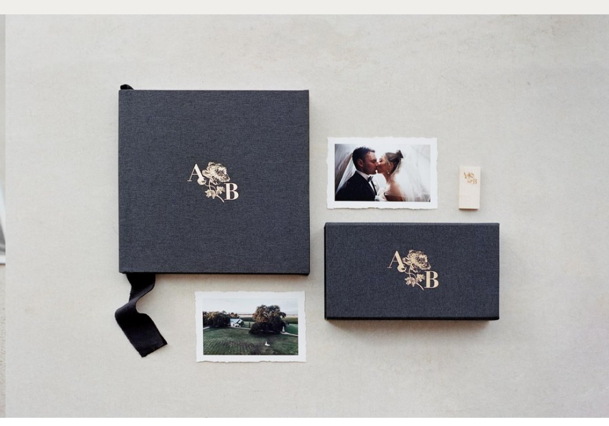 Elegant navy blue wedding album boxes with monogram and photo prints displayed on gray background.