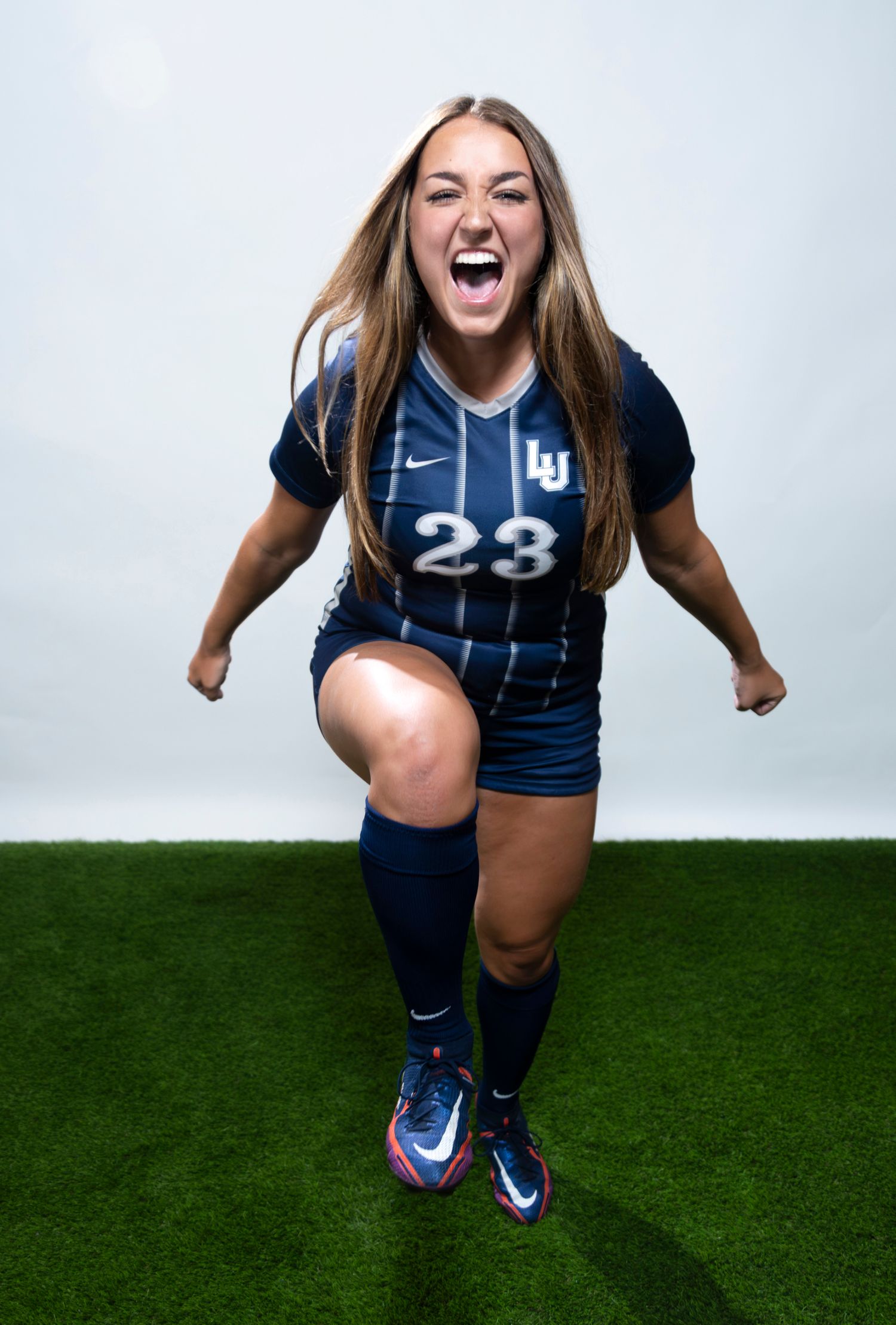 A women's soccer player celebrates during a studio portrait session.