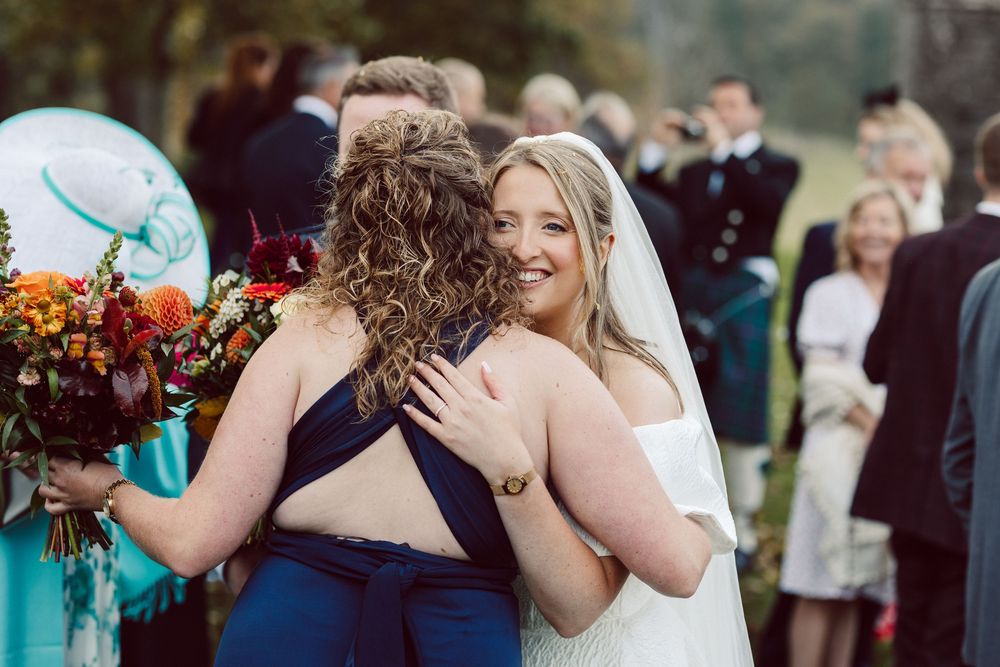 Joyful wedding celebration with guests dancing and embracing at an outdoor reception venue.