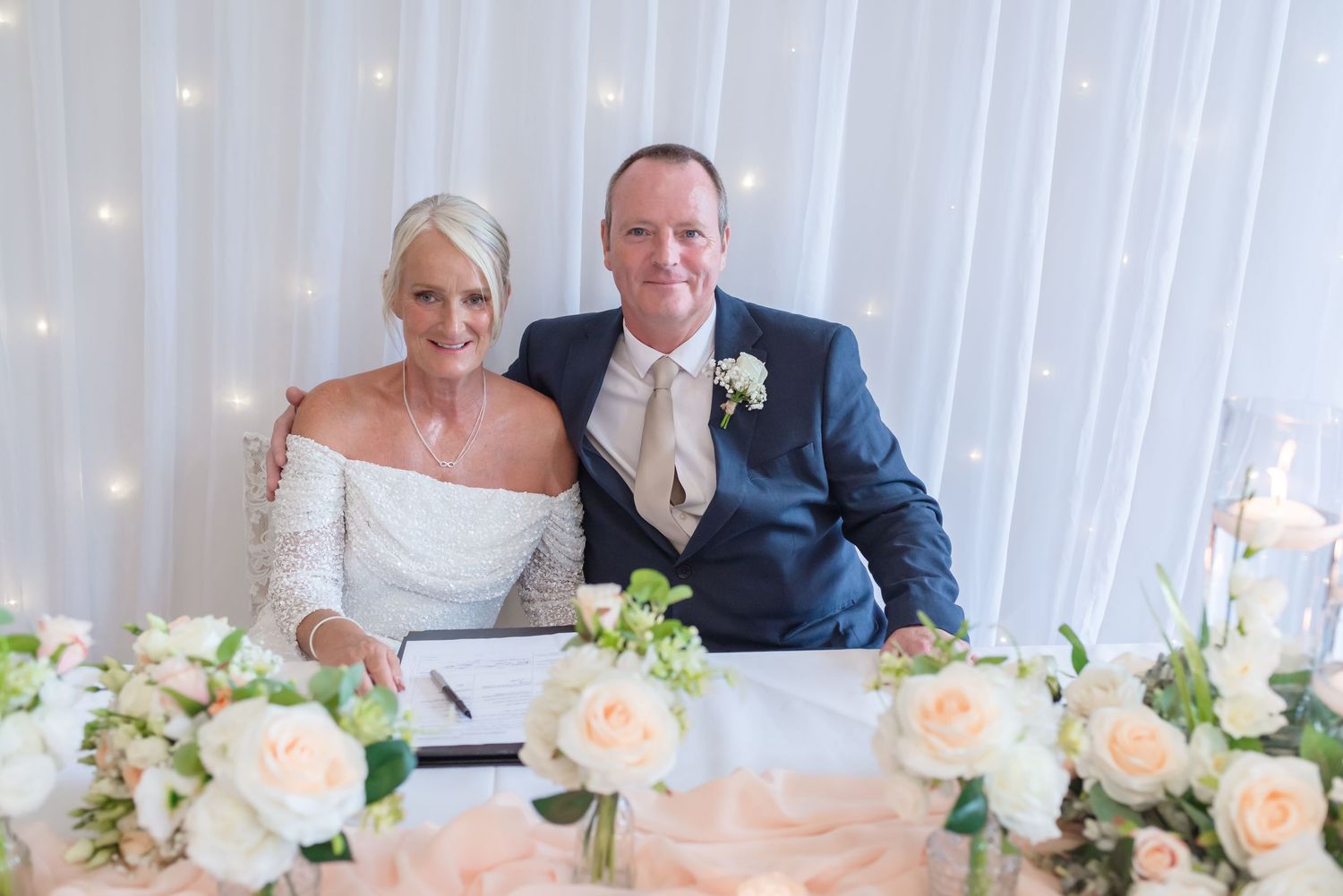 Elegant wedding reception table decor at De Vere Cranage Estate featuring peach roses and white candles; luxury Cheshire wedding photography
