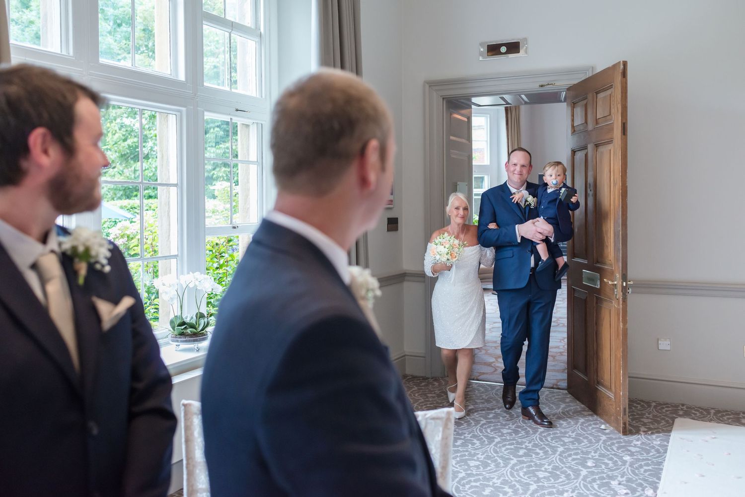 Emotional groom's reaction as the bride enters the ornate ceremony room at De Vere Cranage Estate; professional Cheshire wedding photography
