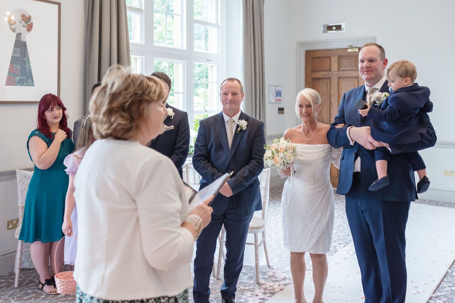 Wedding ceremony at De Vere Cranage Estate; a full bridal party standing during the service in a luxury Cheshire venue by Michael Pardoe