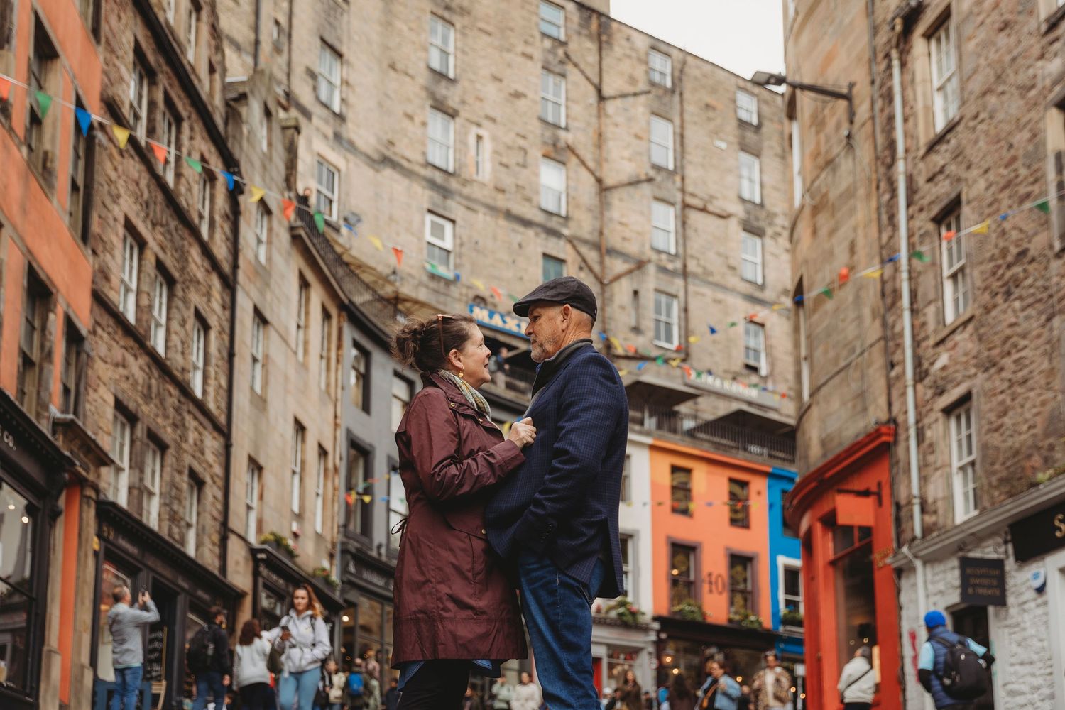 A couple dances together on a cobblestone street between historic stone buildings in Edinburgh's Old Town.