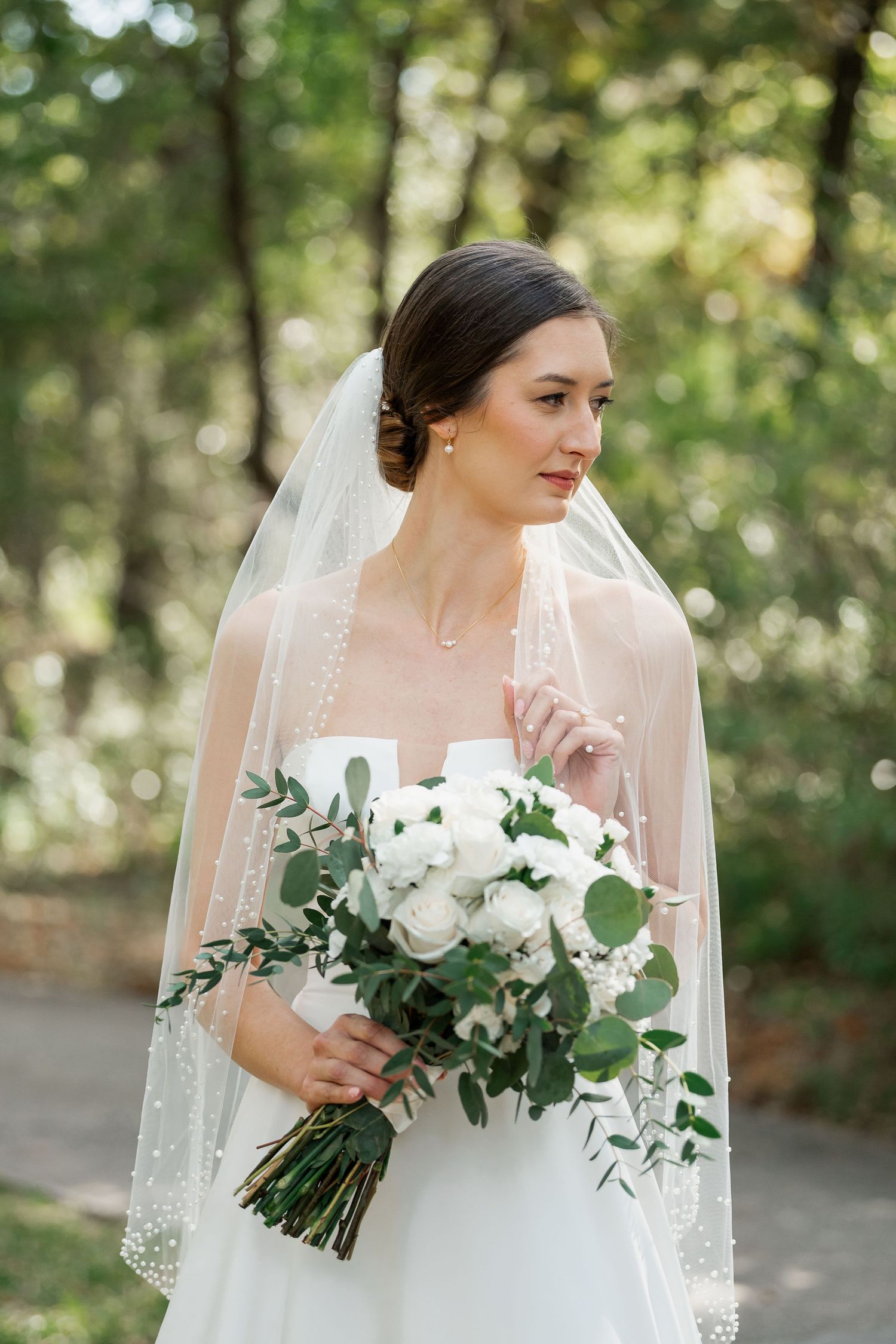 Elegant bridal portraits in a garden setting featuring white roses and eucalyptus bouquet.
