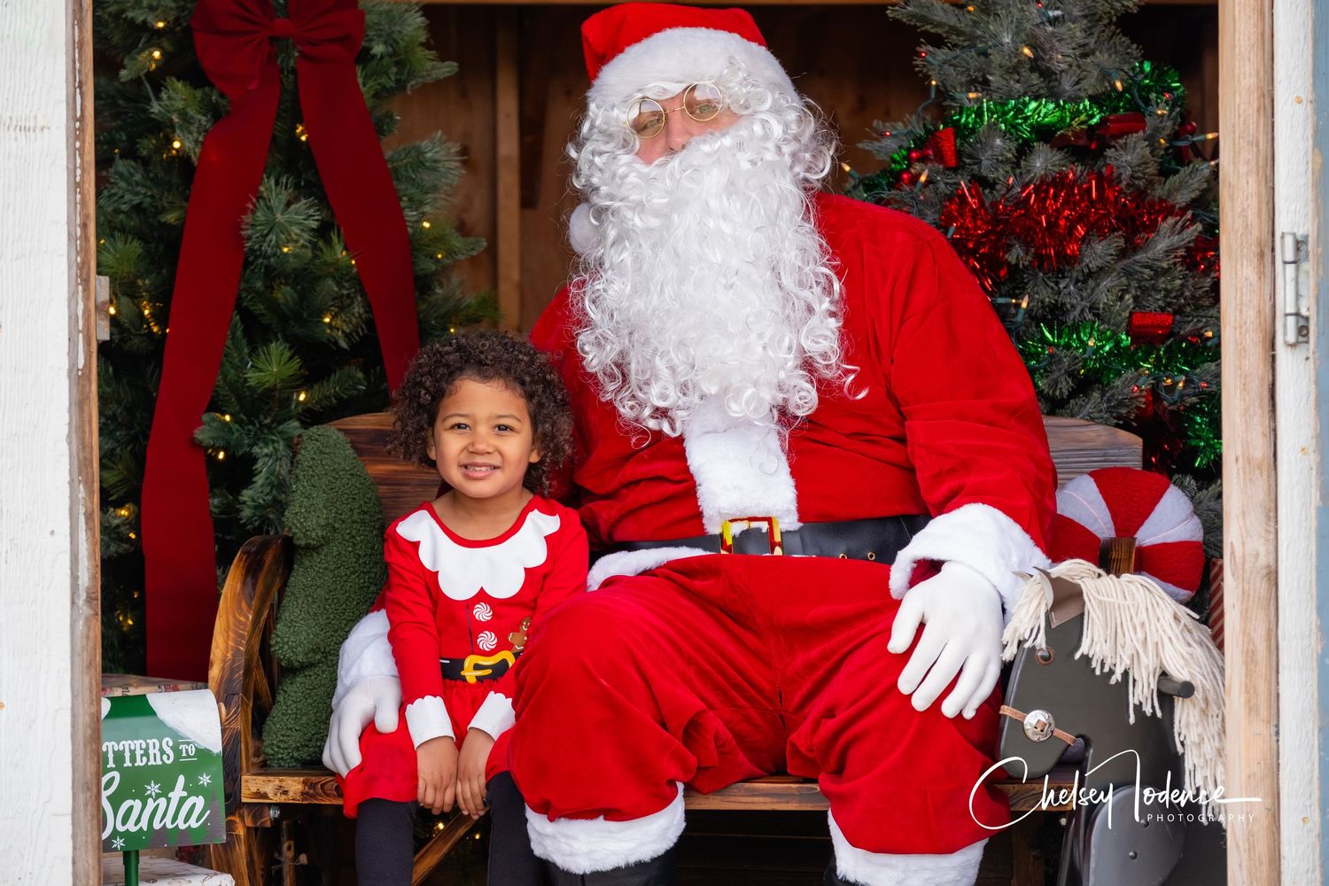 Child smiling with Santa during a festive holiday photo session in Sonoma County, California surrounded by Christmas decor