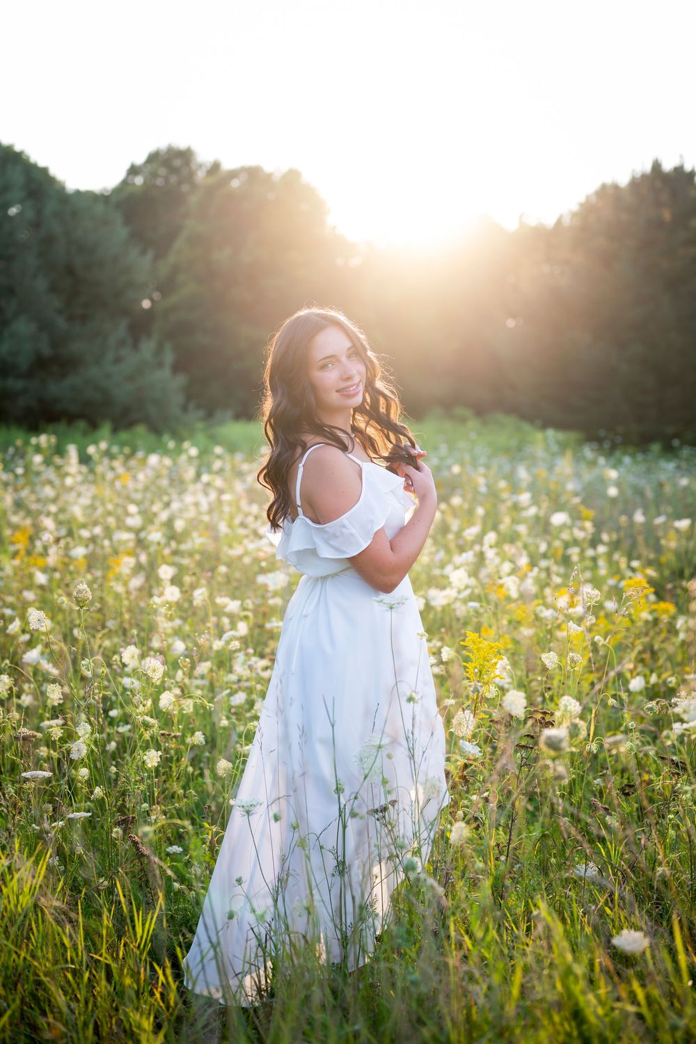 Ethereal white dress catches light in a wildflower meadow during golden hour.