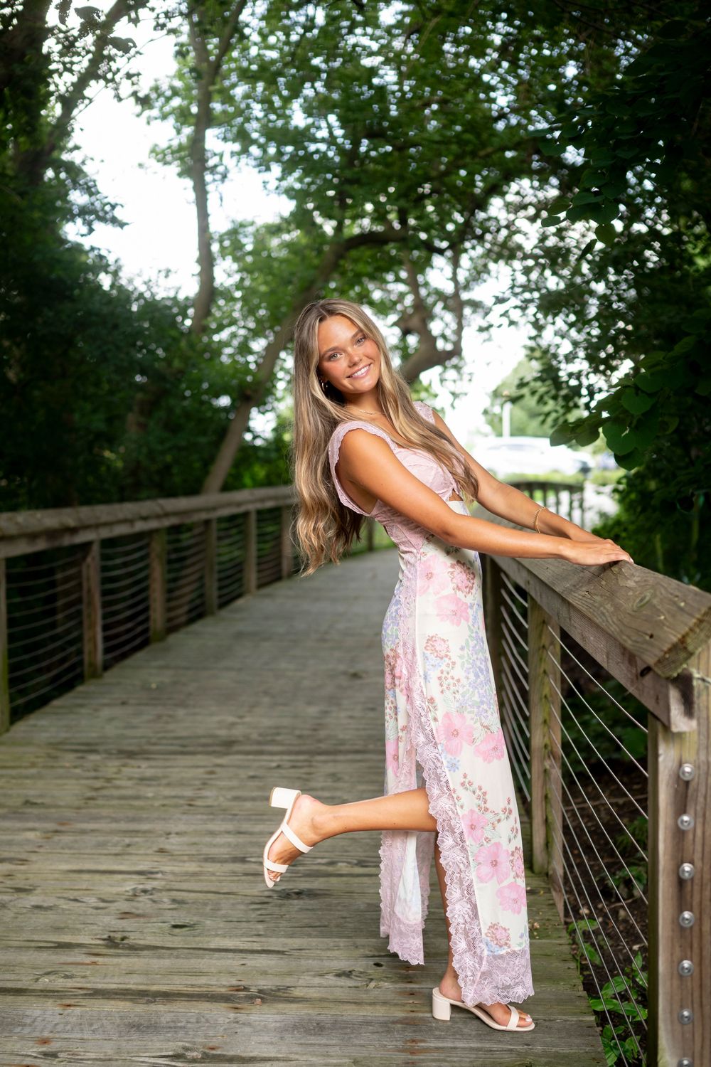 Playful poses captured on a wooden boardwalk surrounded by lush green trees.